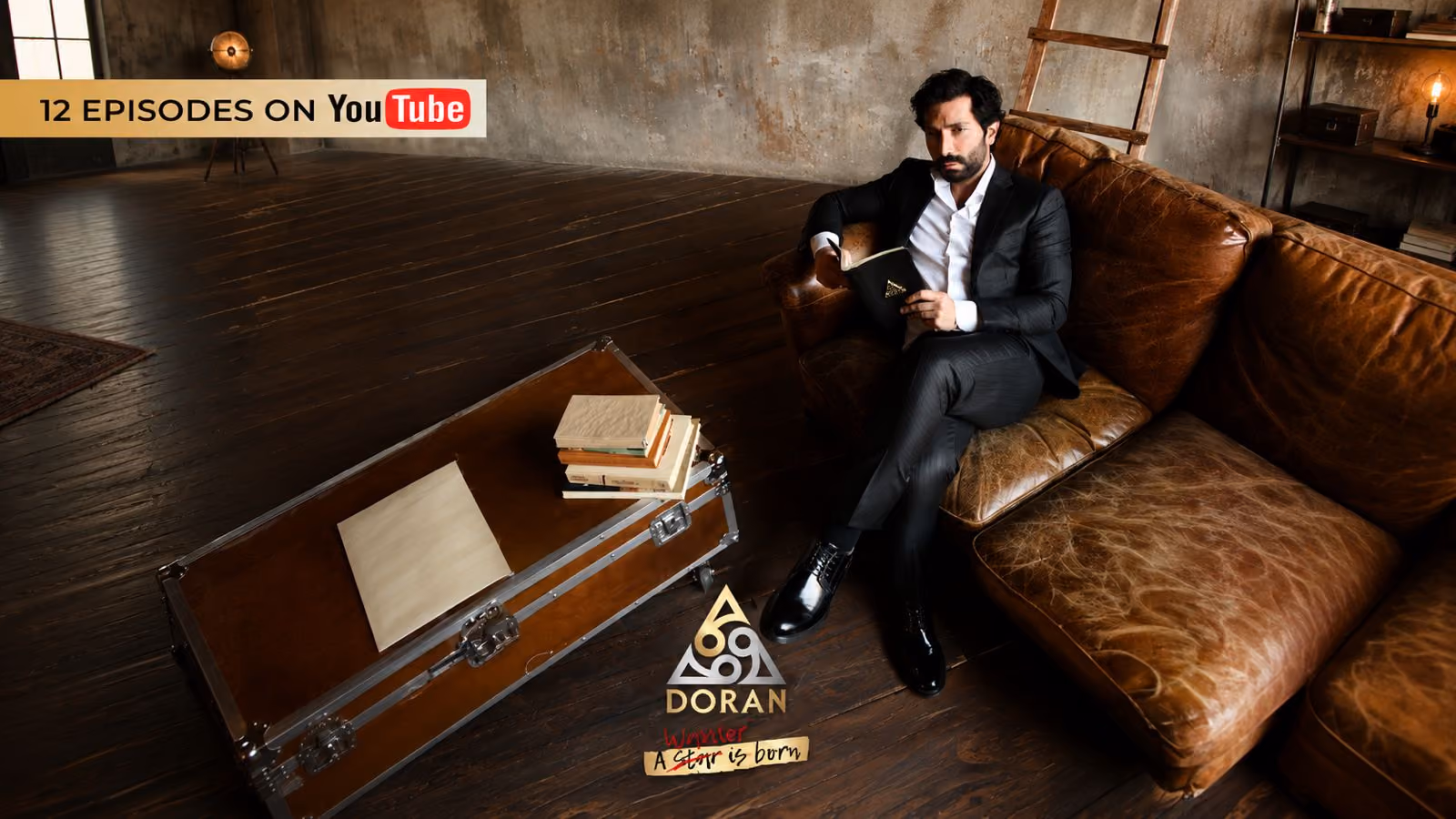 Donato Lecce in a dark suit sitting on a leather sofa while reading a book in a room with a dark wooden floor.