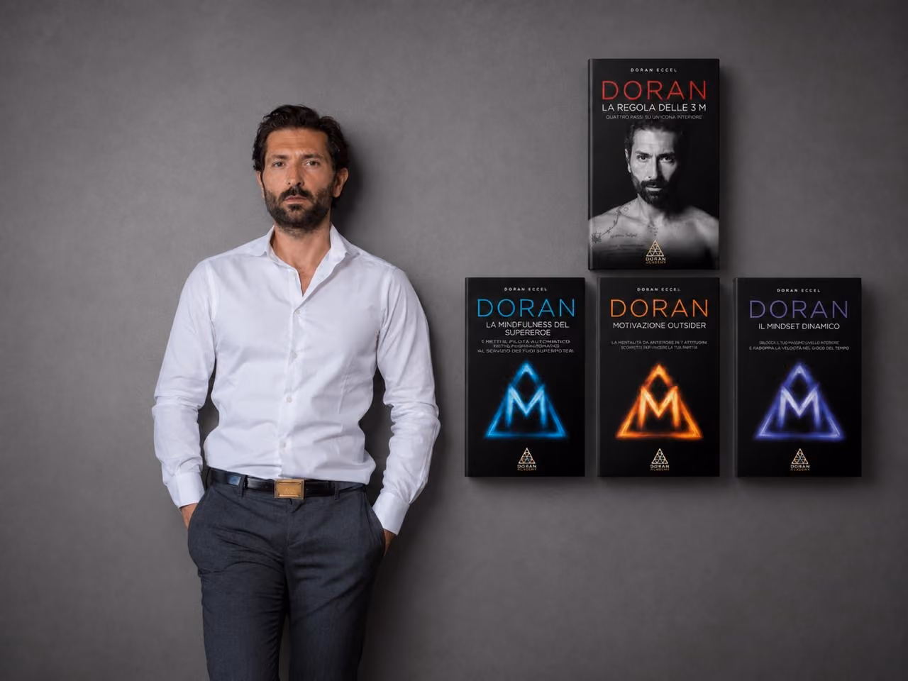 Man in a white shirt next to four Doran books with black covers and colorful titles.