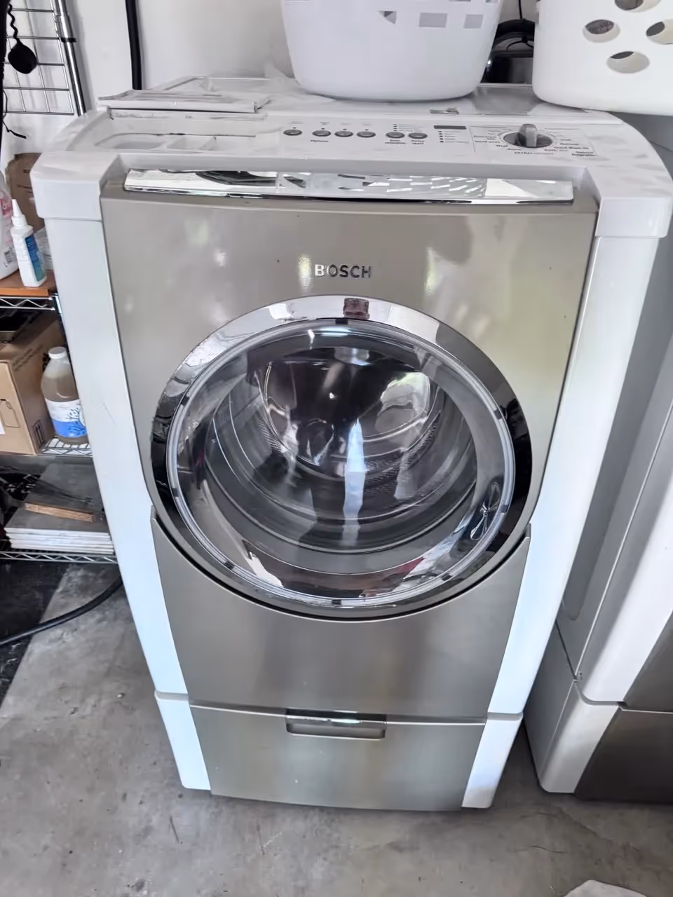 Bosch front-load washer with large chrome door in laundry area.