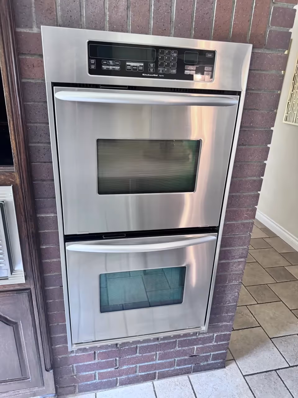 KitchenAid stainless steel double wall oven built into a brick kitchen wall