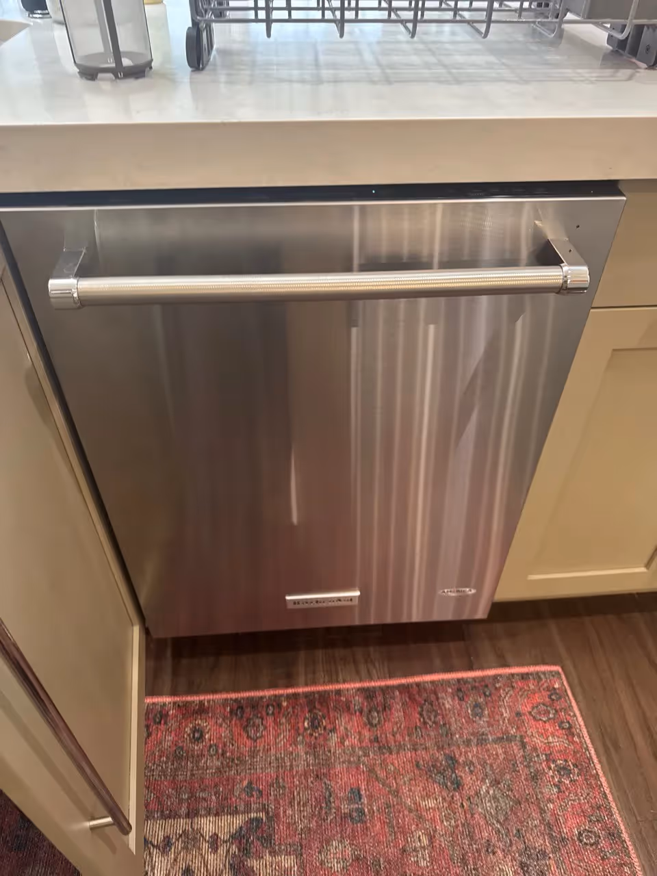 KitchenAid stainless steel dishwasher with a bar handle installed under a quartz countertop