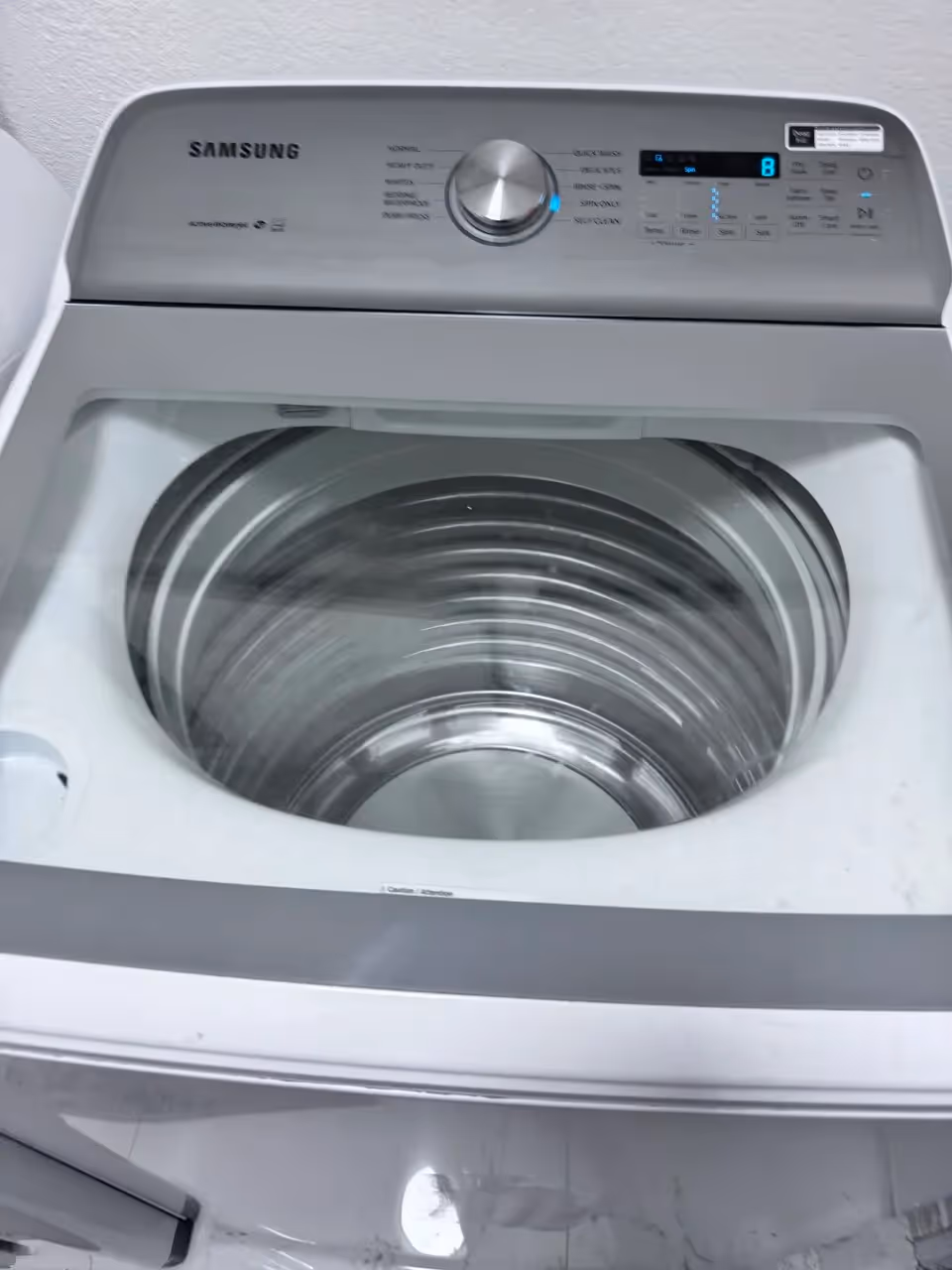 Samsung top-load washer with stainless steel drum and digital control panel.