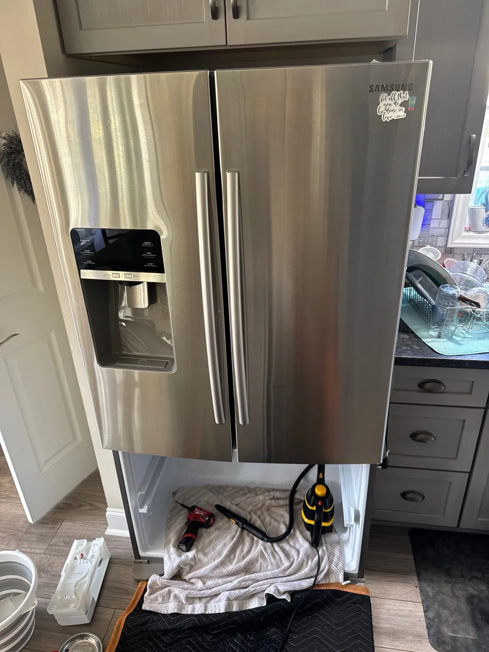 Samsung side-by-side stainless steel refrigerator during repair with freezer open.