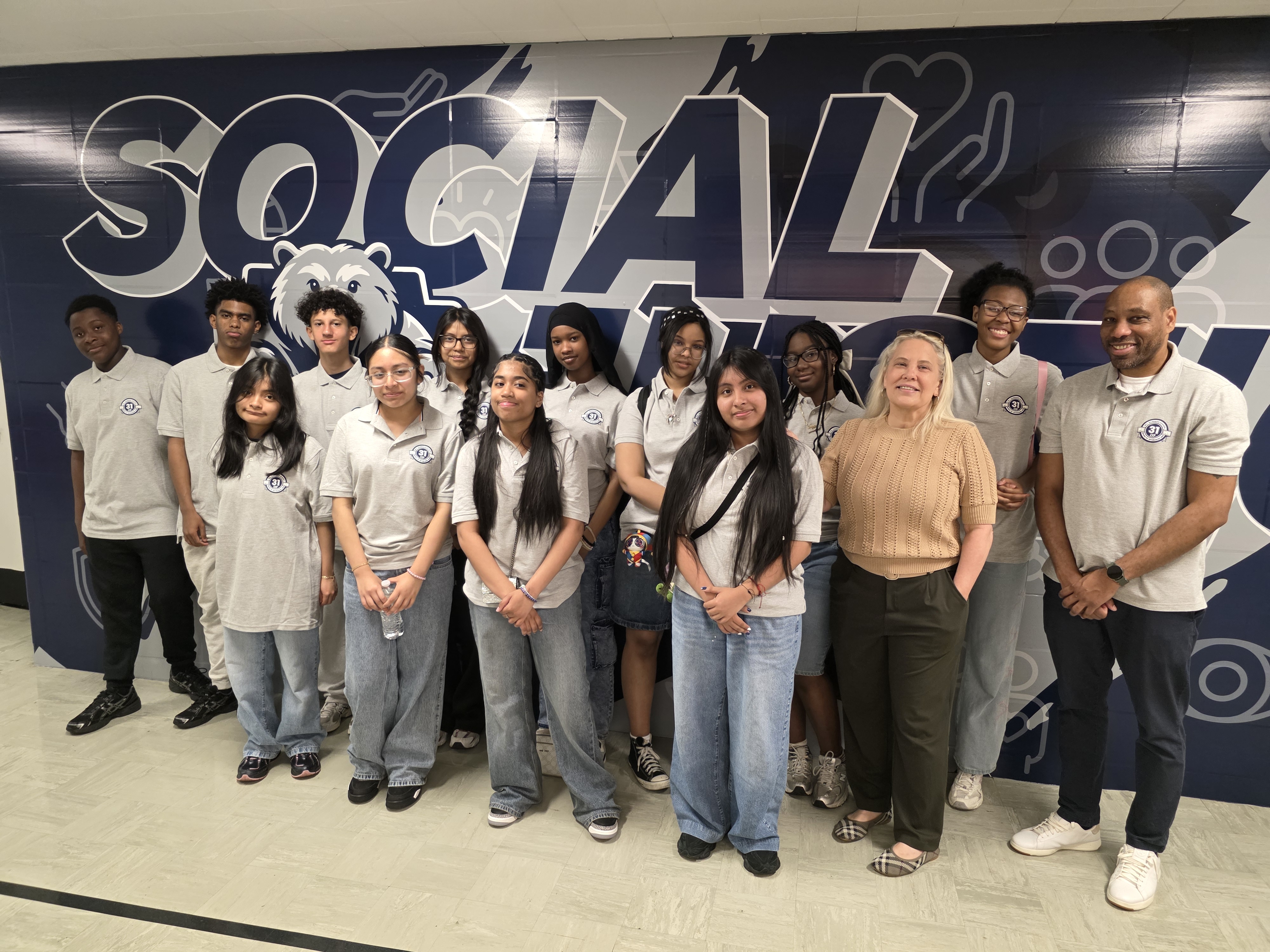 Students and staff posing in front of school Social Skills mural