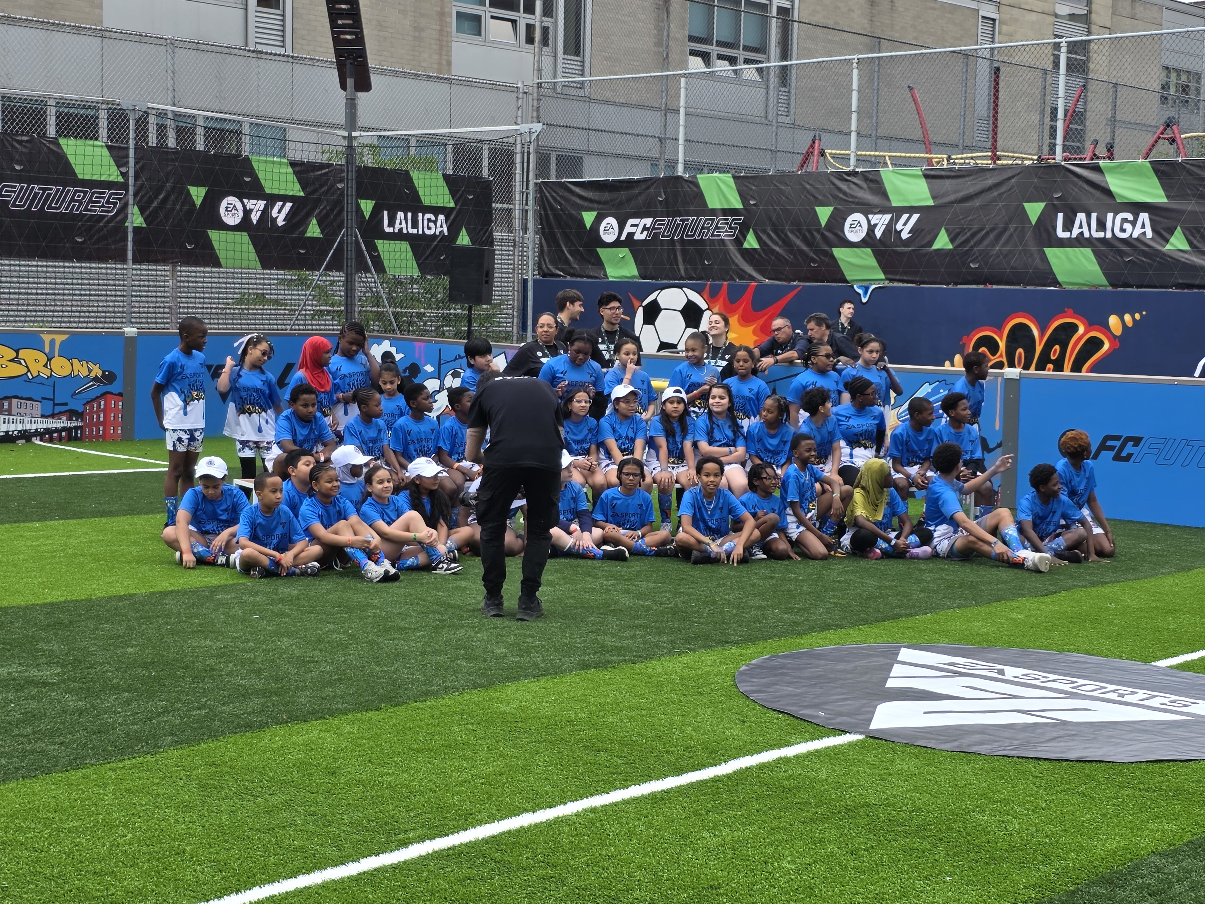 Students in blue shirts pose on soccer field at EA FC Futures event