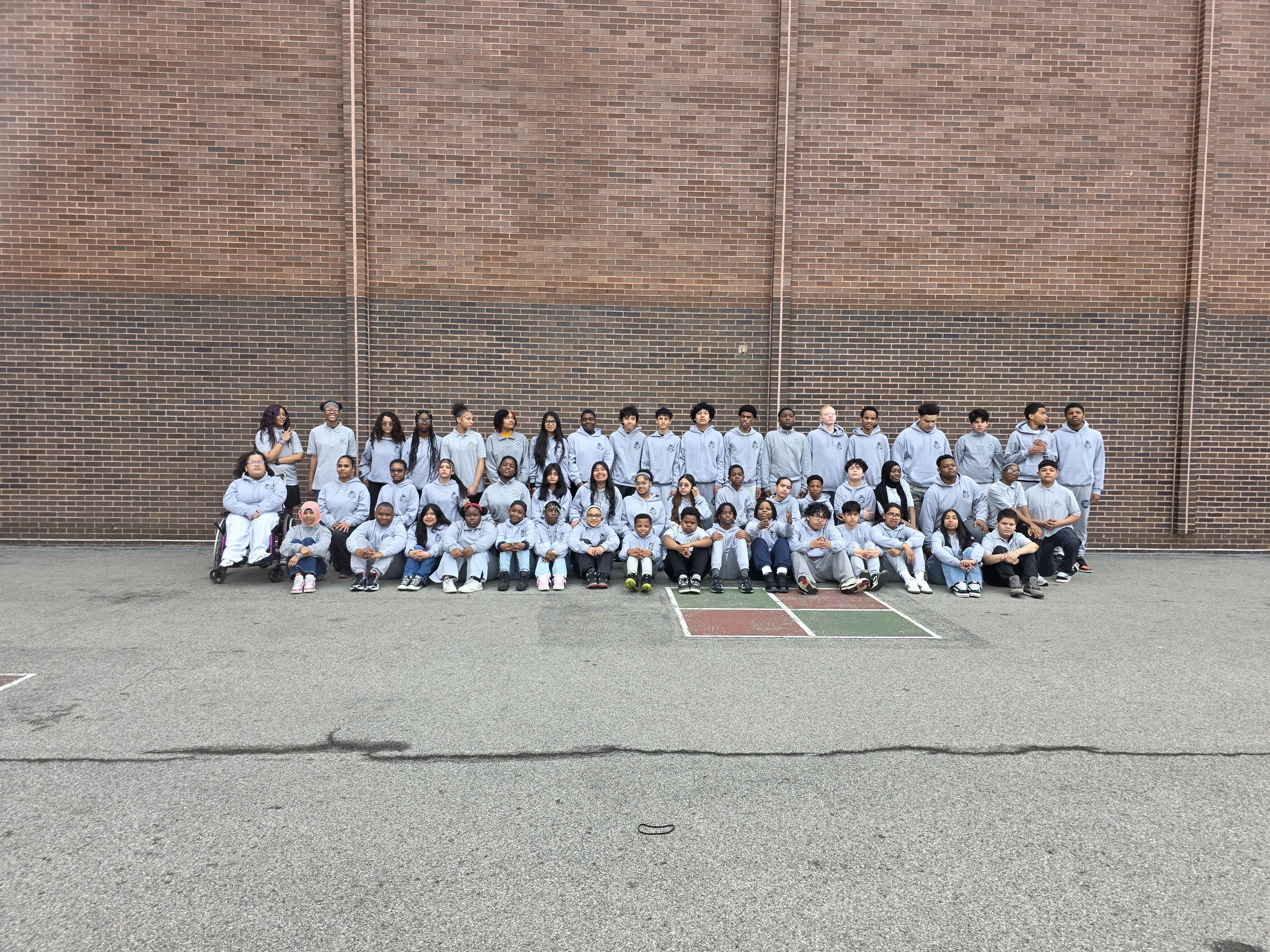 Large group of students in matching gray hoodies posing outdoors