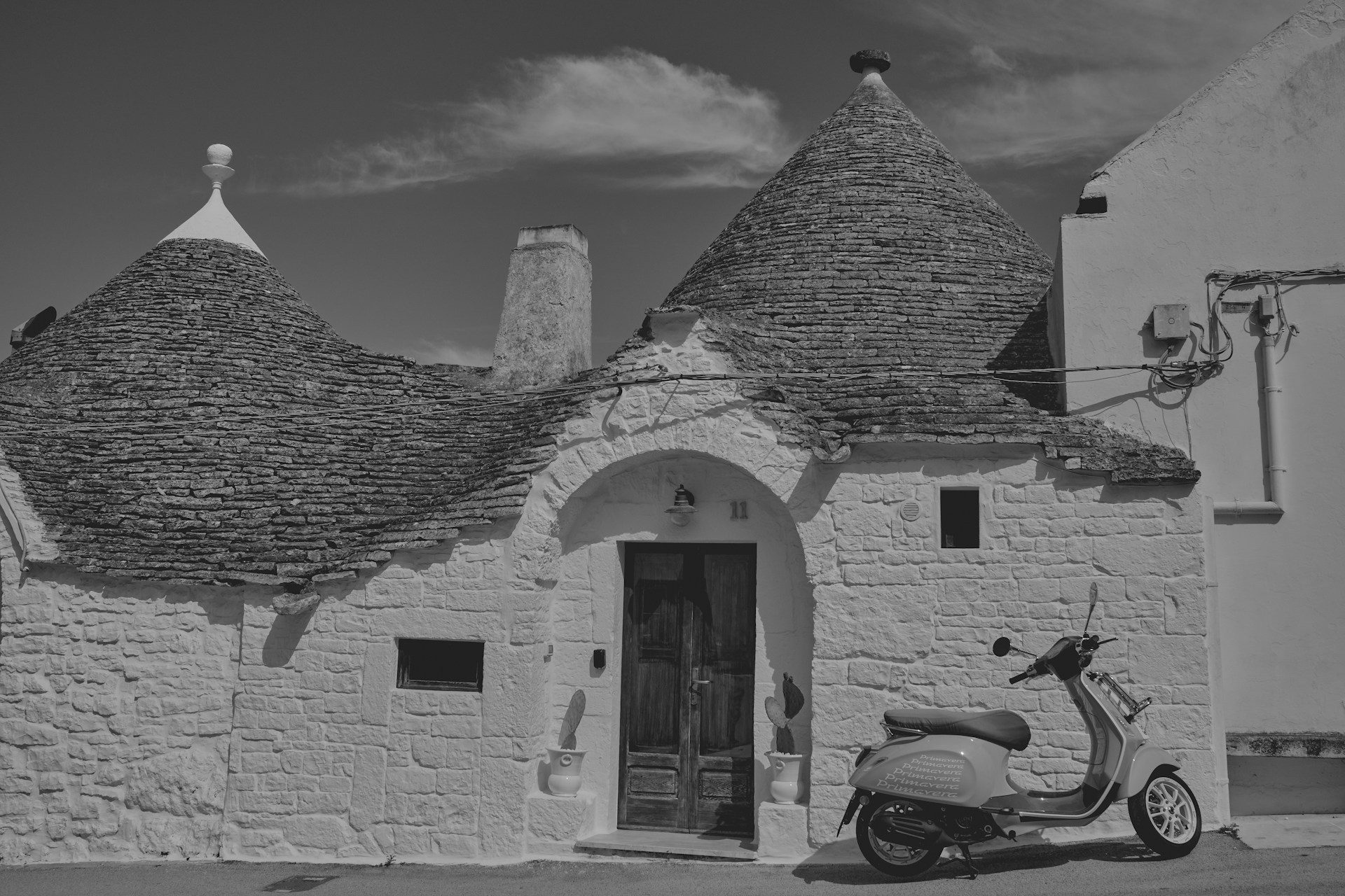 A narrow limestone alley in an old Apulian village with a vintage blue Ape truck passing through