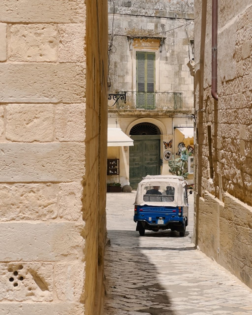 A black and white photograph of a traditional trullo with a Vespa parked outside in Alberobello
