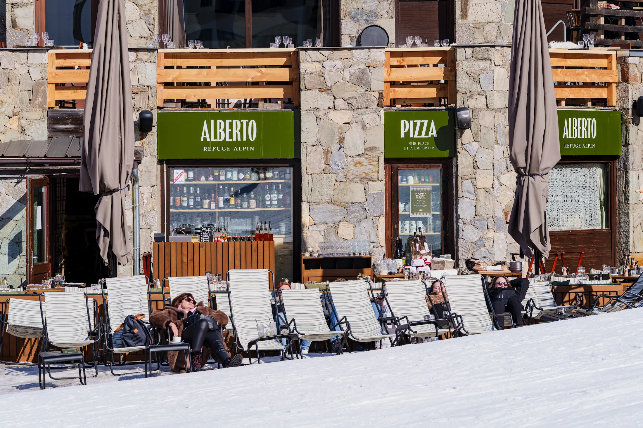 Cliente se reposant dans un transat devant le restaurant Alberto Tignes, terrasse ensoleillée à Tignes Val-Claret.