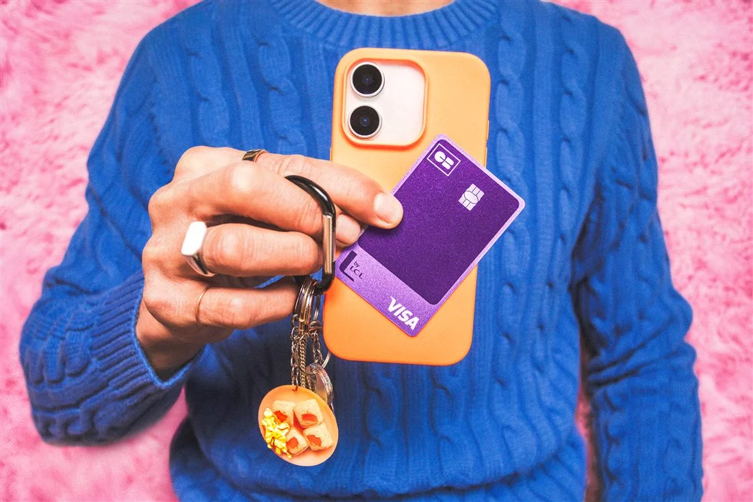 Main tenant un téléphone orange et une carte CB Visa violette