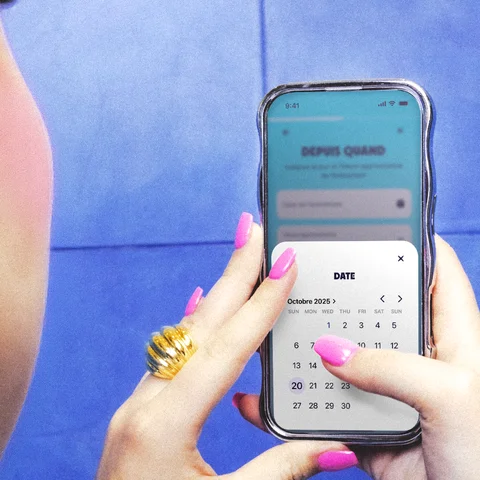 Mains tenant un smartphone affichant un sélecteur de date dans l'application, sur fond de carrelage bleu