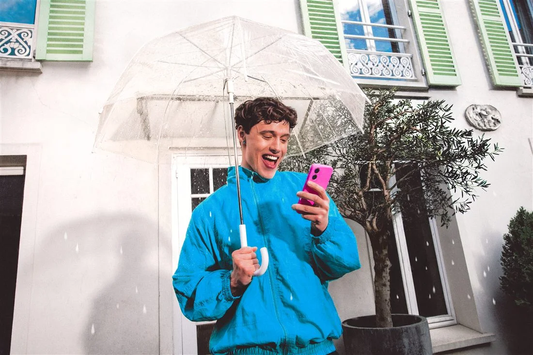 Homme en veste bleue avec un parapluie transparent tenant un téléphone rose