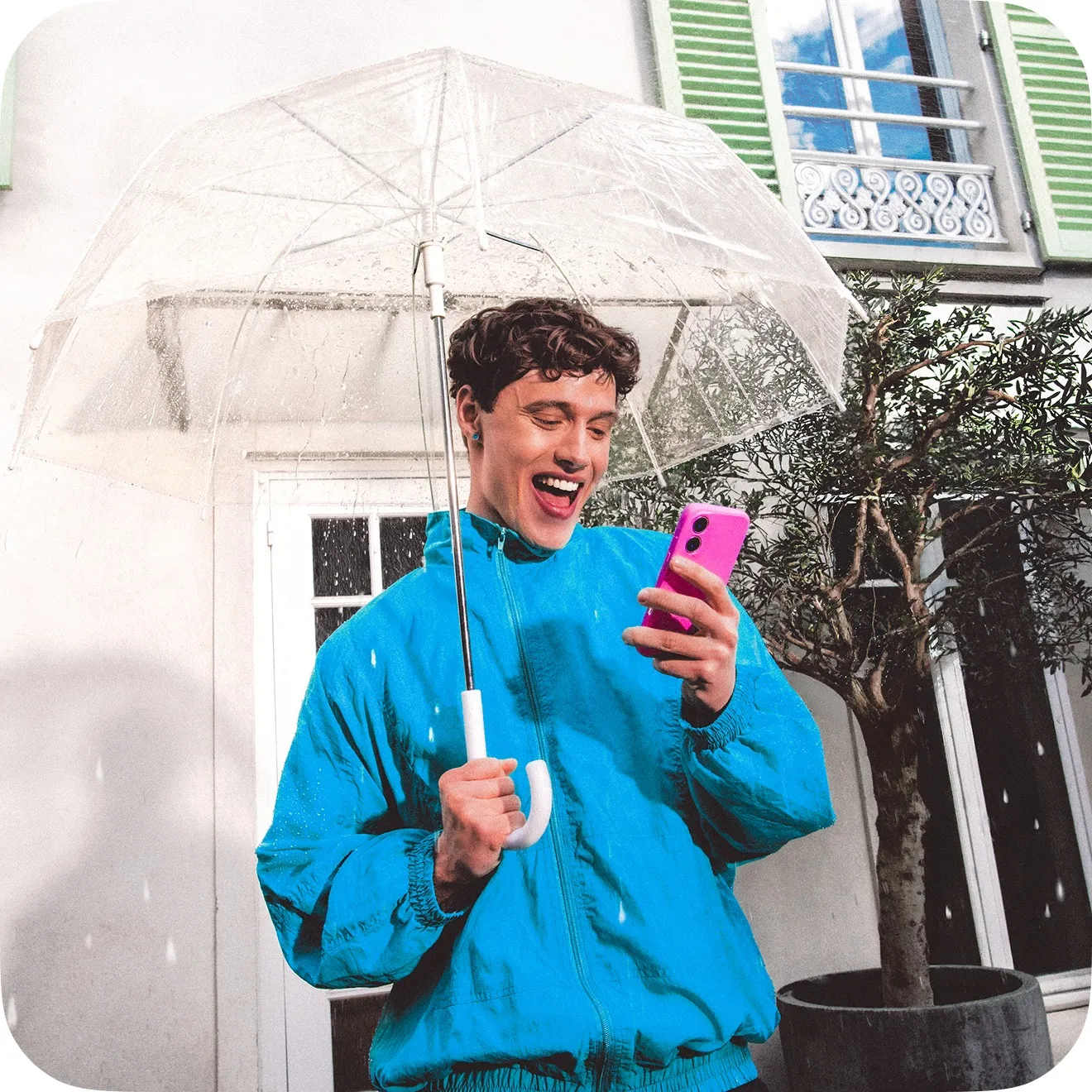 Personne souriante sous un parapluie transparent, regardant son téléphone