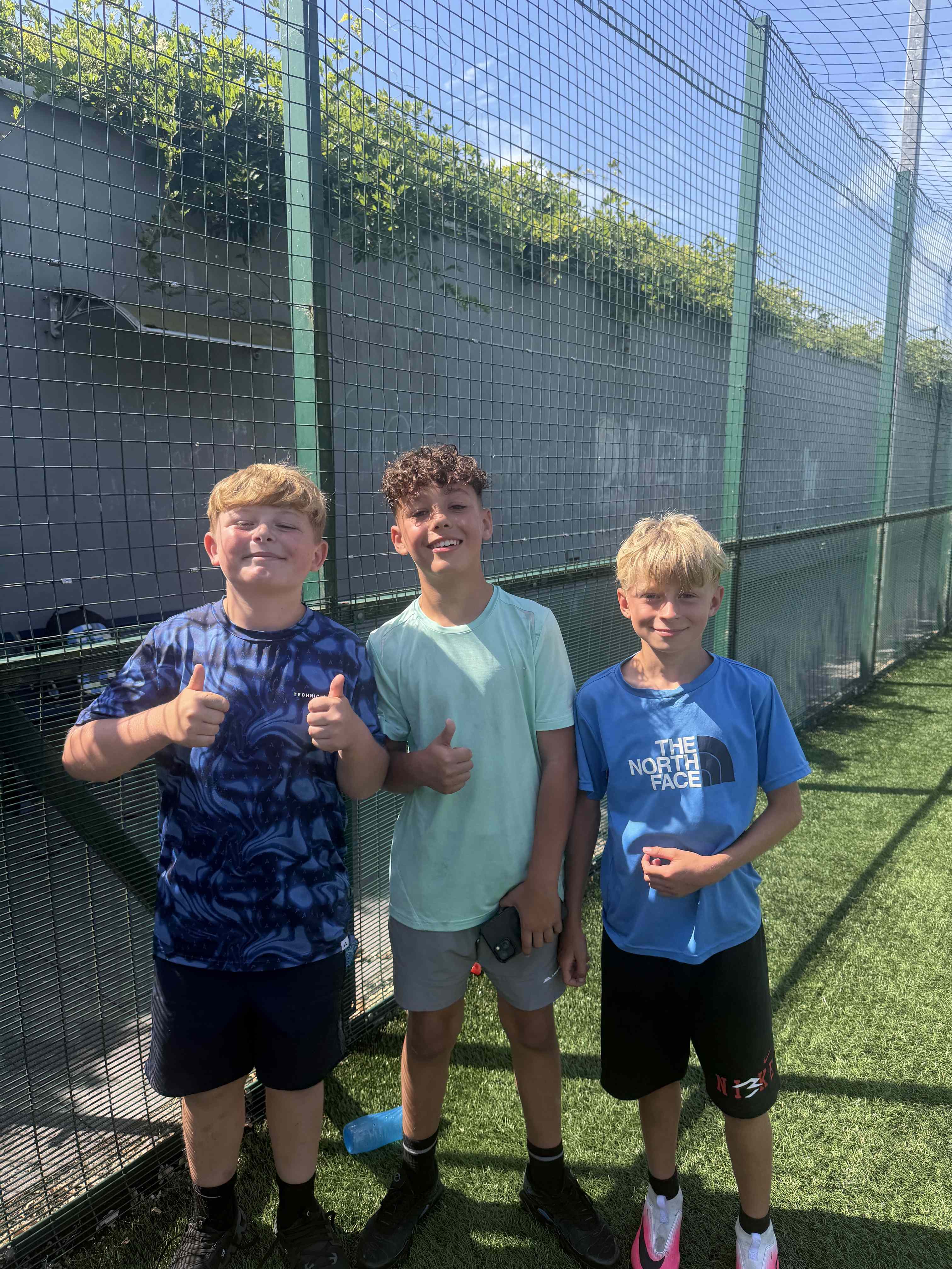 3 young people stood posing for a photo on the 3g pitch