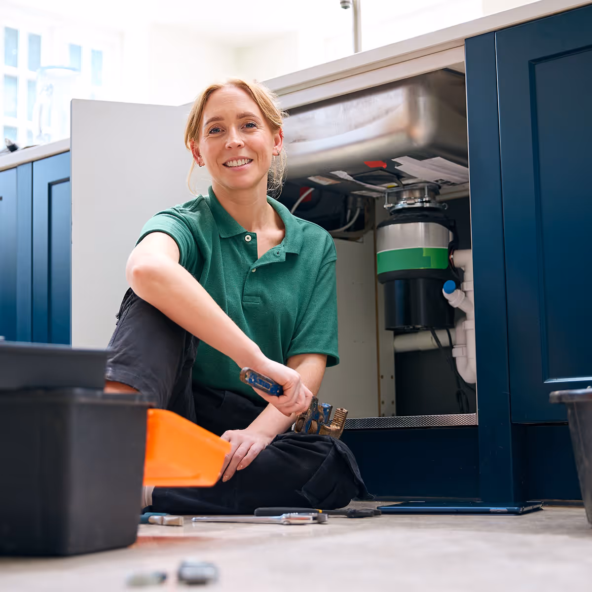 A smiling plumber who has been working under a sink.