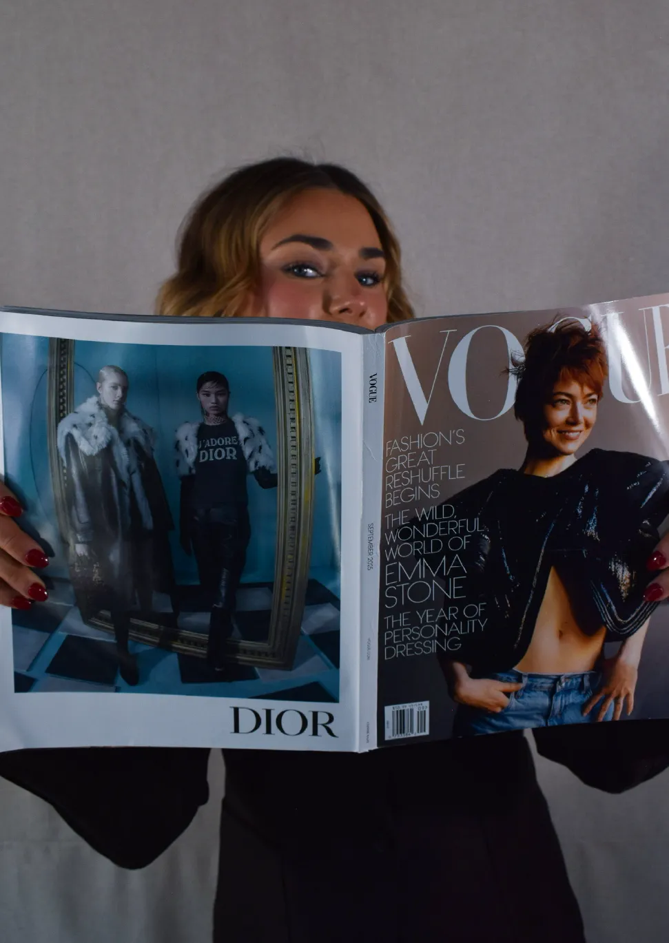 Person holding an open Vogue magazine with Emma Stone featured on the cover and a Dior fashion ad on the opposite page.