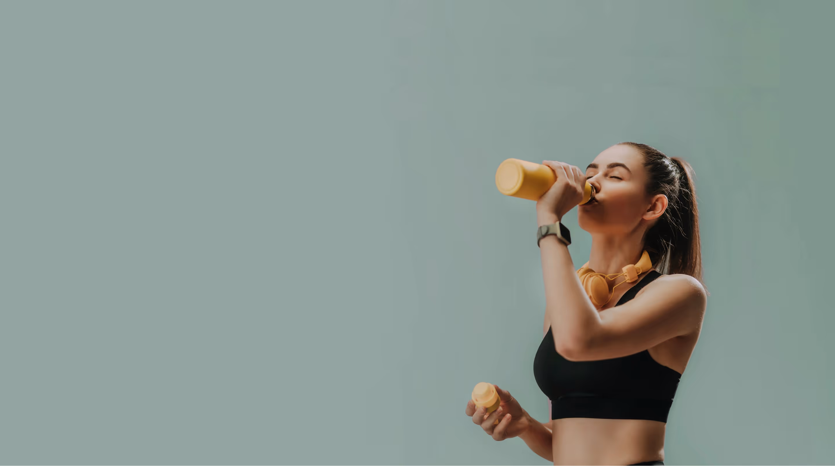 Woman in sportswear drinking from a yellow bottle.