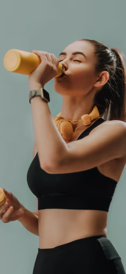 Woman in sportswear drinking from a yellow bottle.