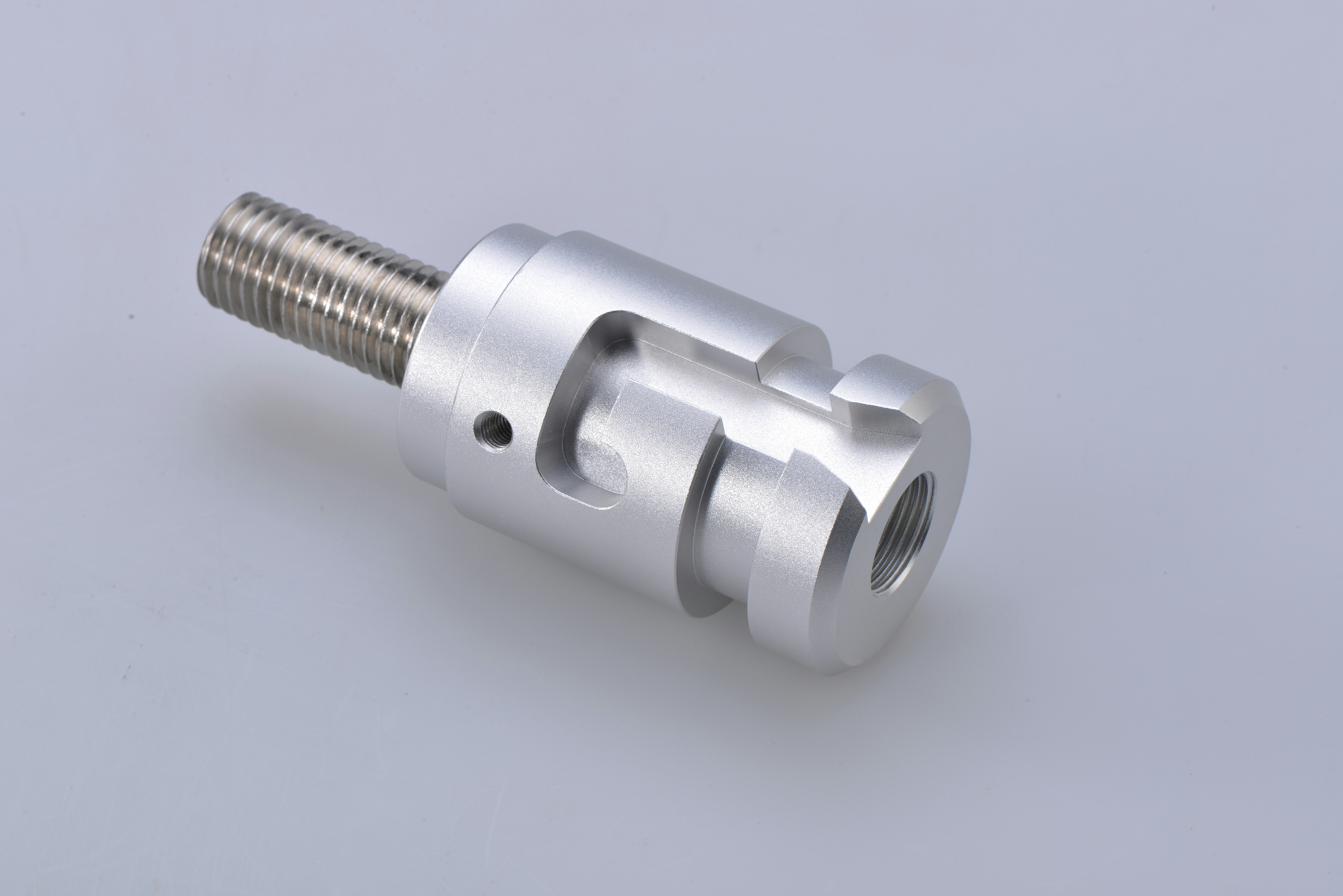 Close-up of a silver metal mechanical component with a threaded bolt and cylindrical body.
