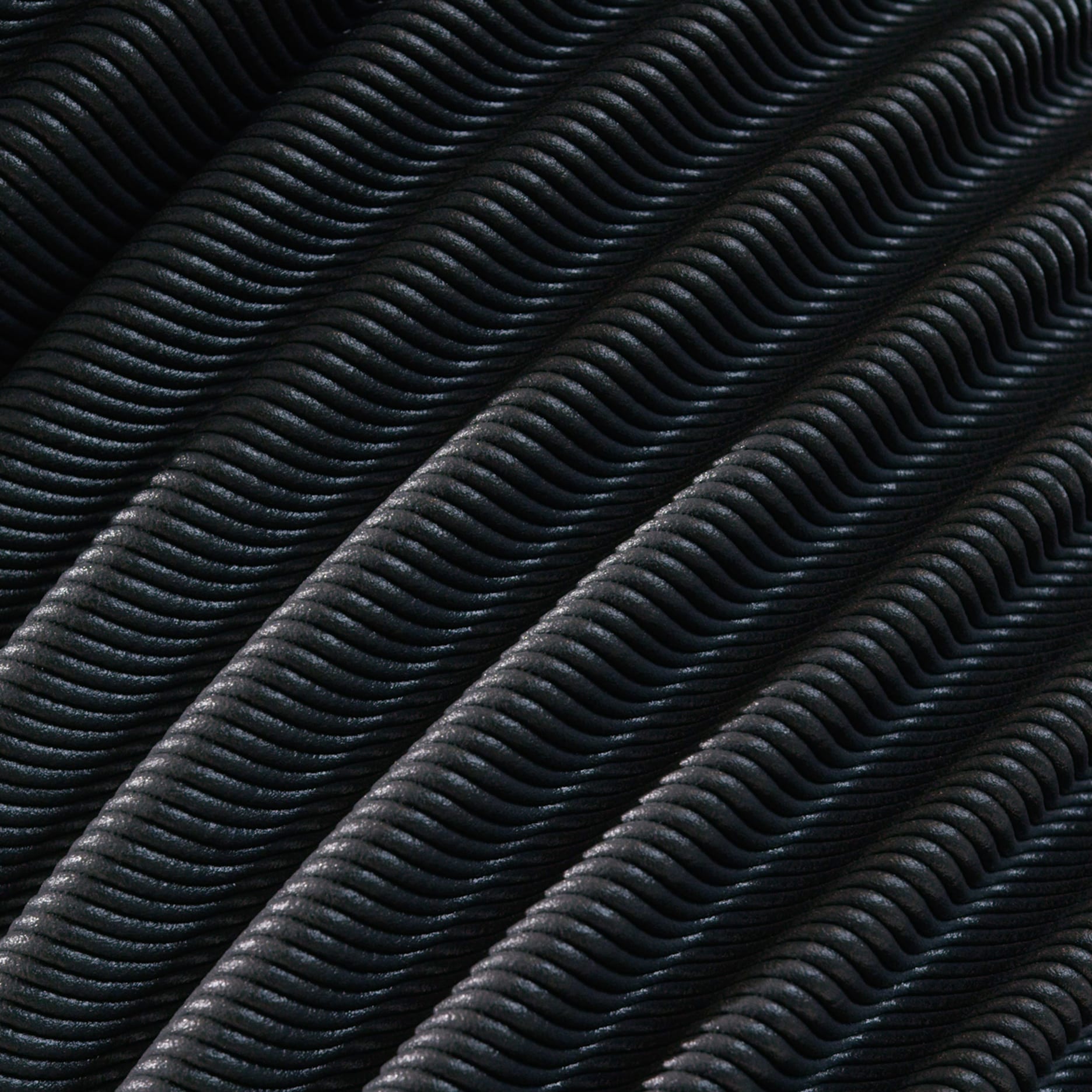 Close-up of dark wavy textured material arranged in parallel diagonal folds.