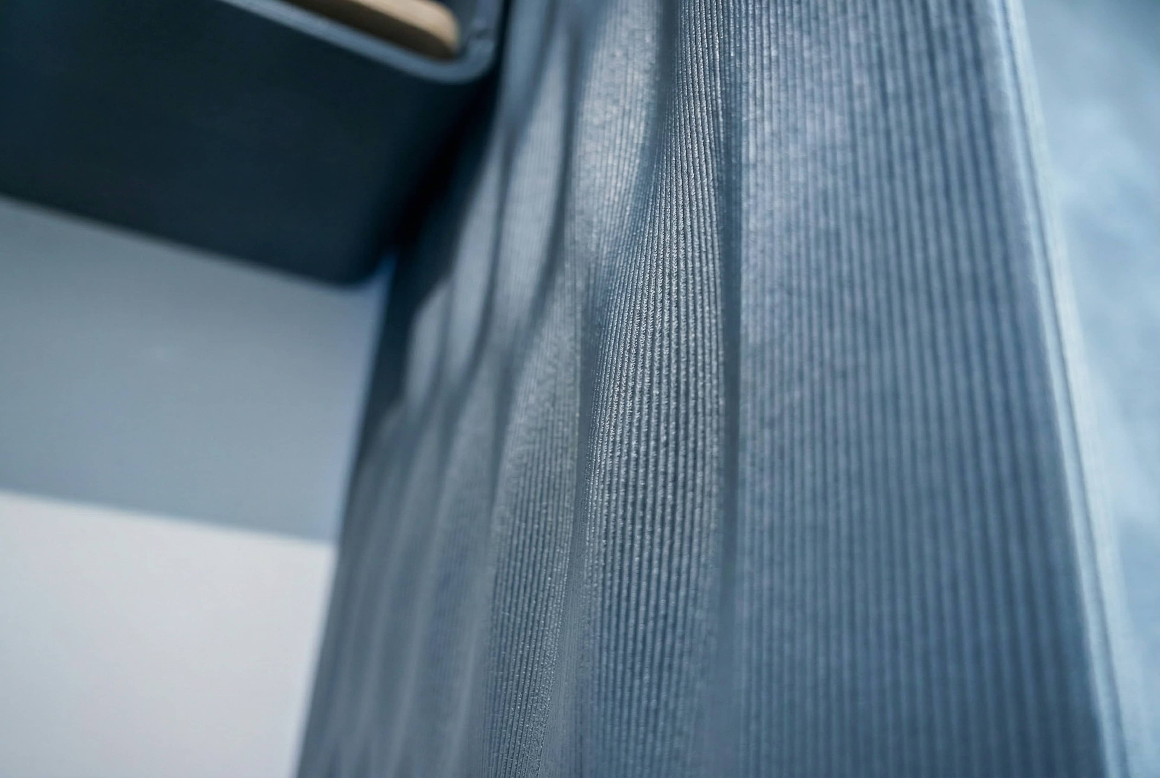 Close-up of a dark blue yoga mat curled in overlapping loops on a light surface.