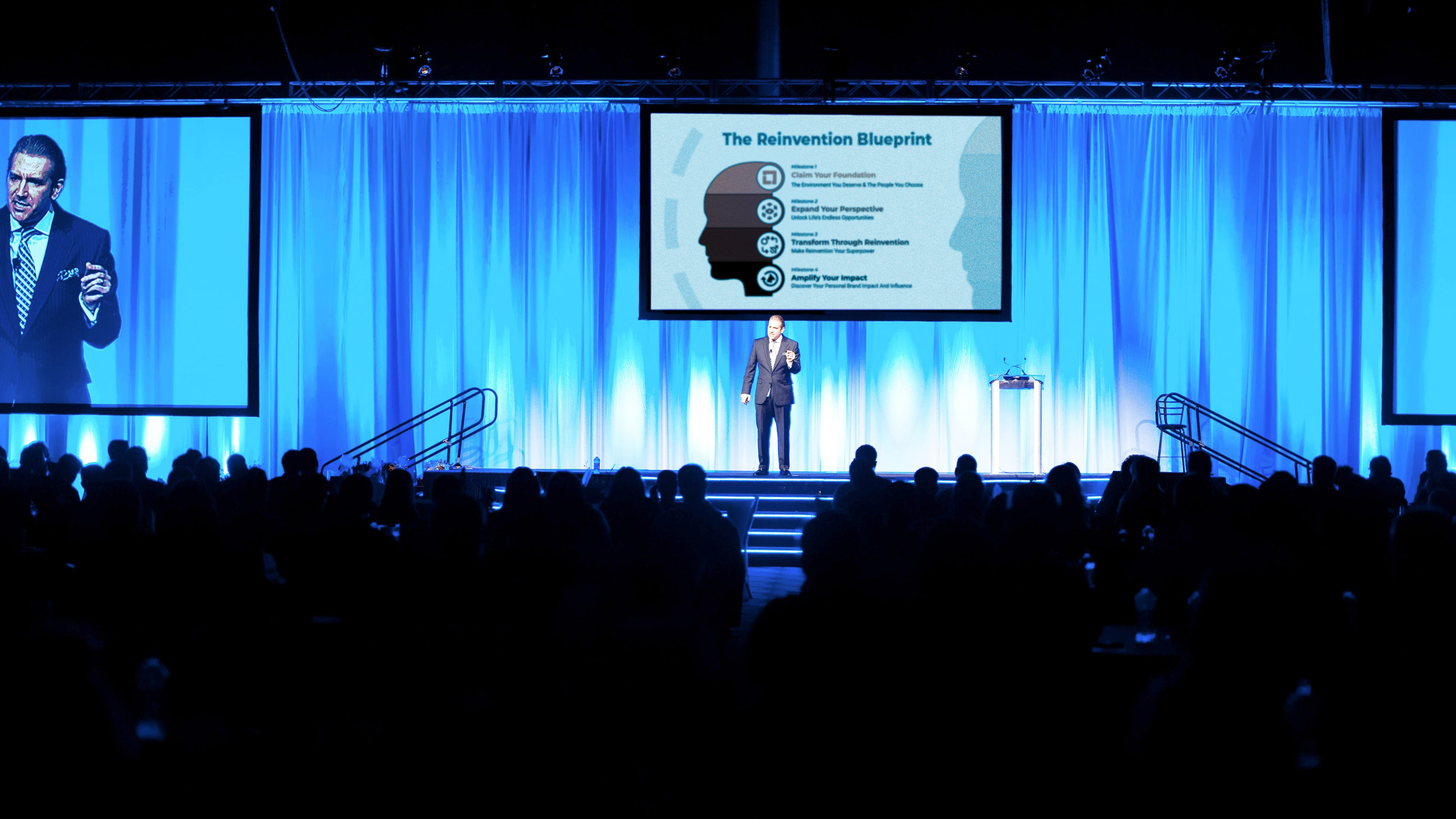 Glenn Llopis presenting The Reinvention Blueprint on stage at a leadership conference, with audience in attendance and visual slides highlighting personal transformation milestones.