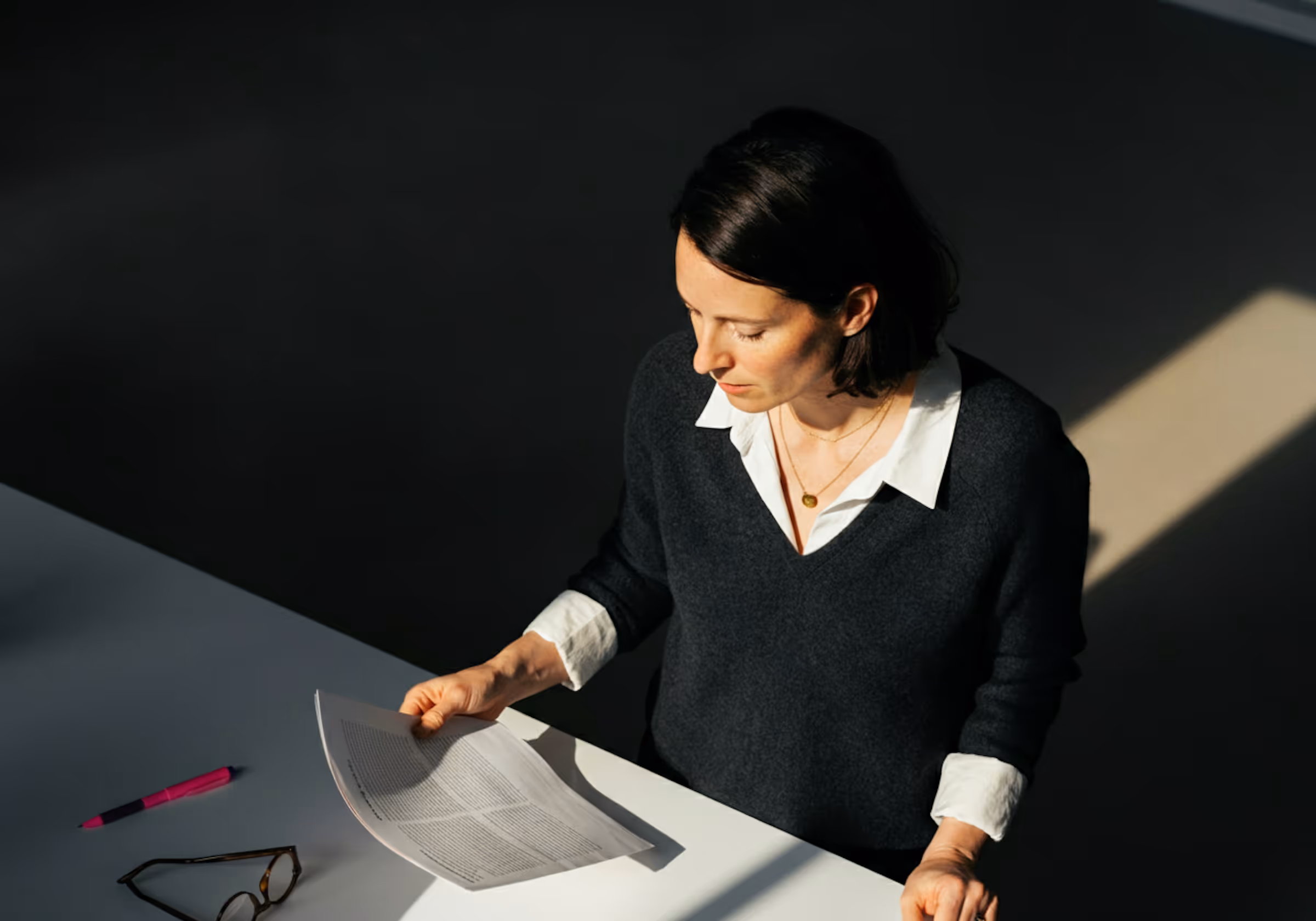 A woman sitting at a table with a piece of paper in front of her.