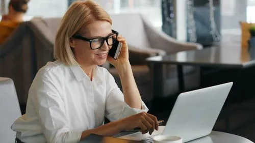 A woman wearing glasses and a white shirt is using a laptop.