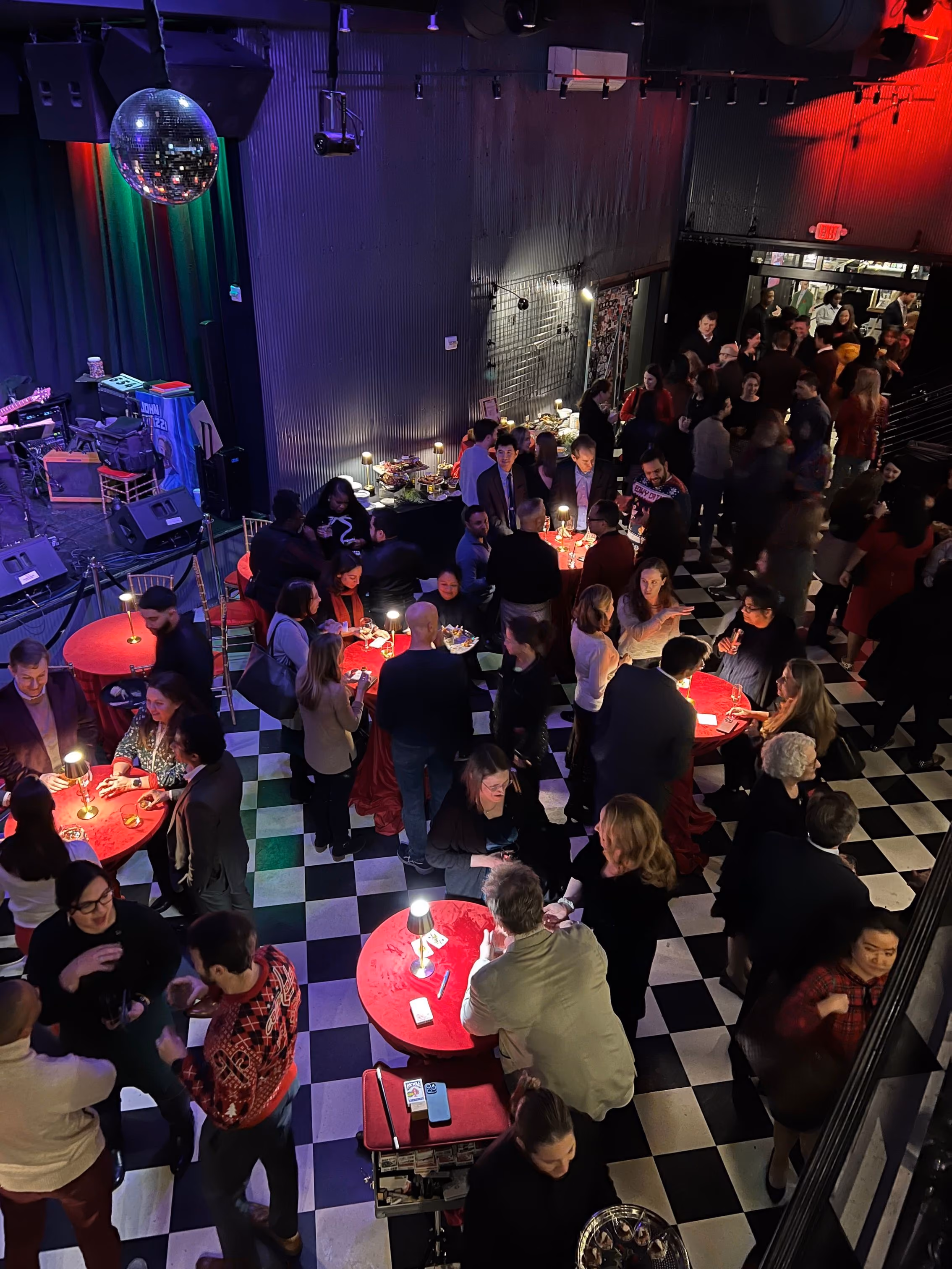Guests mingling around red cocktail tables at a private event at Pearl Street Warehouse