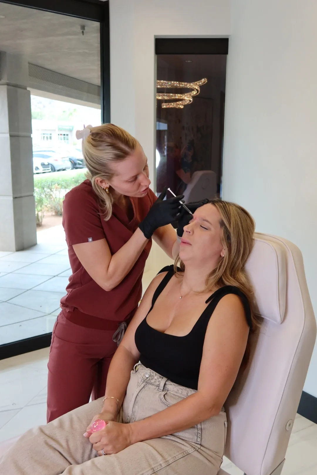 Client relaxing in a treatment chair while receiving forehead Botox