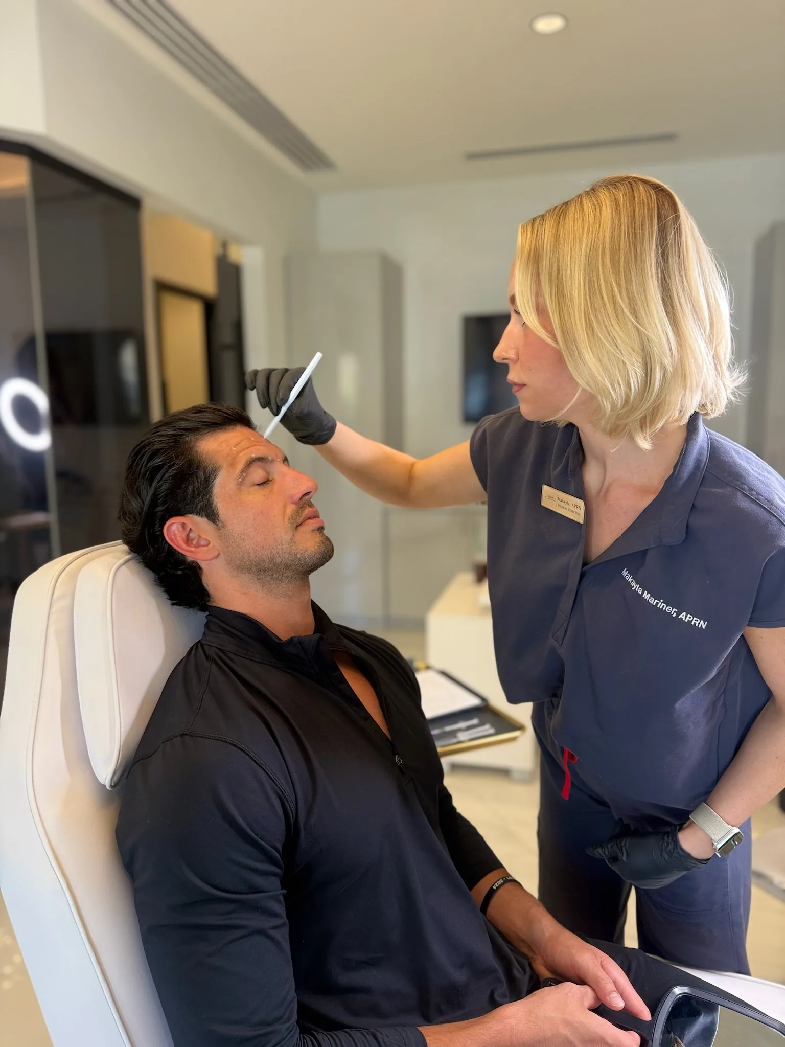 Injector marking treatment points on a male client's forehead before Botox