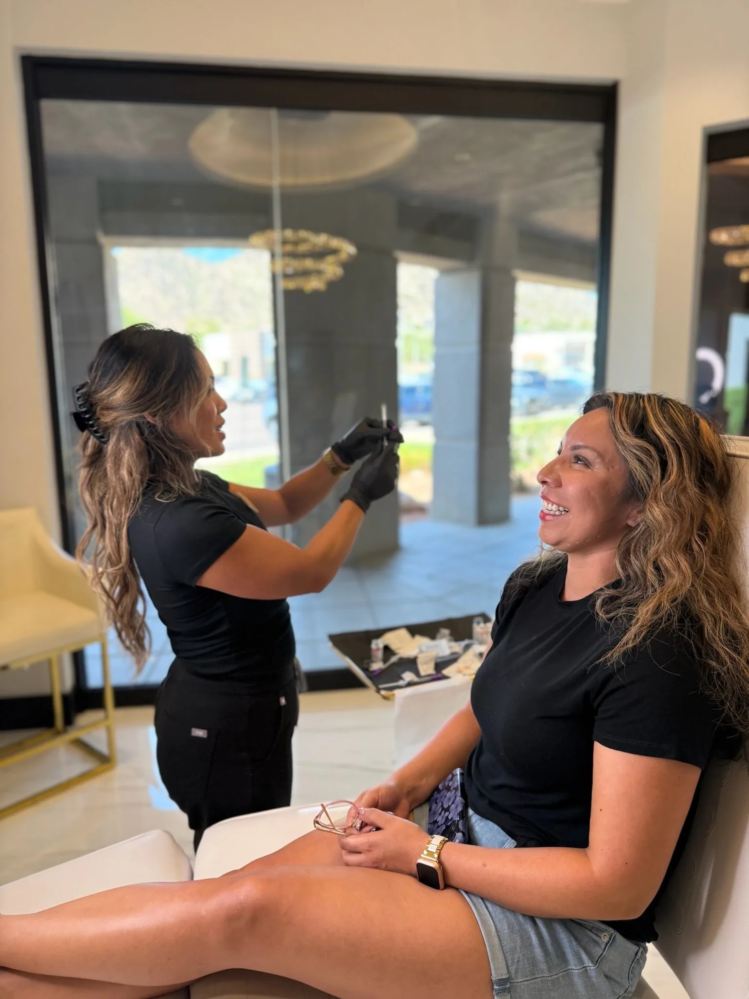 Injector preparing a Botox syringe while a smiling client waits