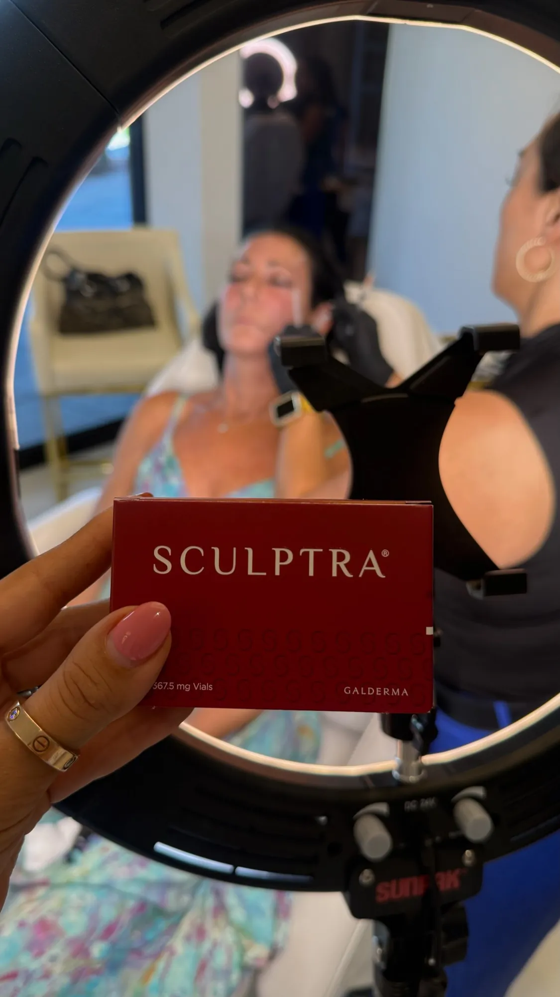 Sculptra box in focus with a provider treating a client's cheek in the background.