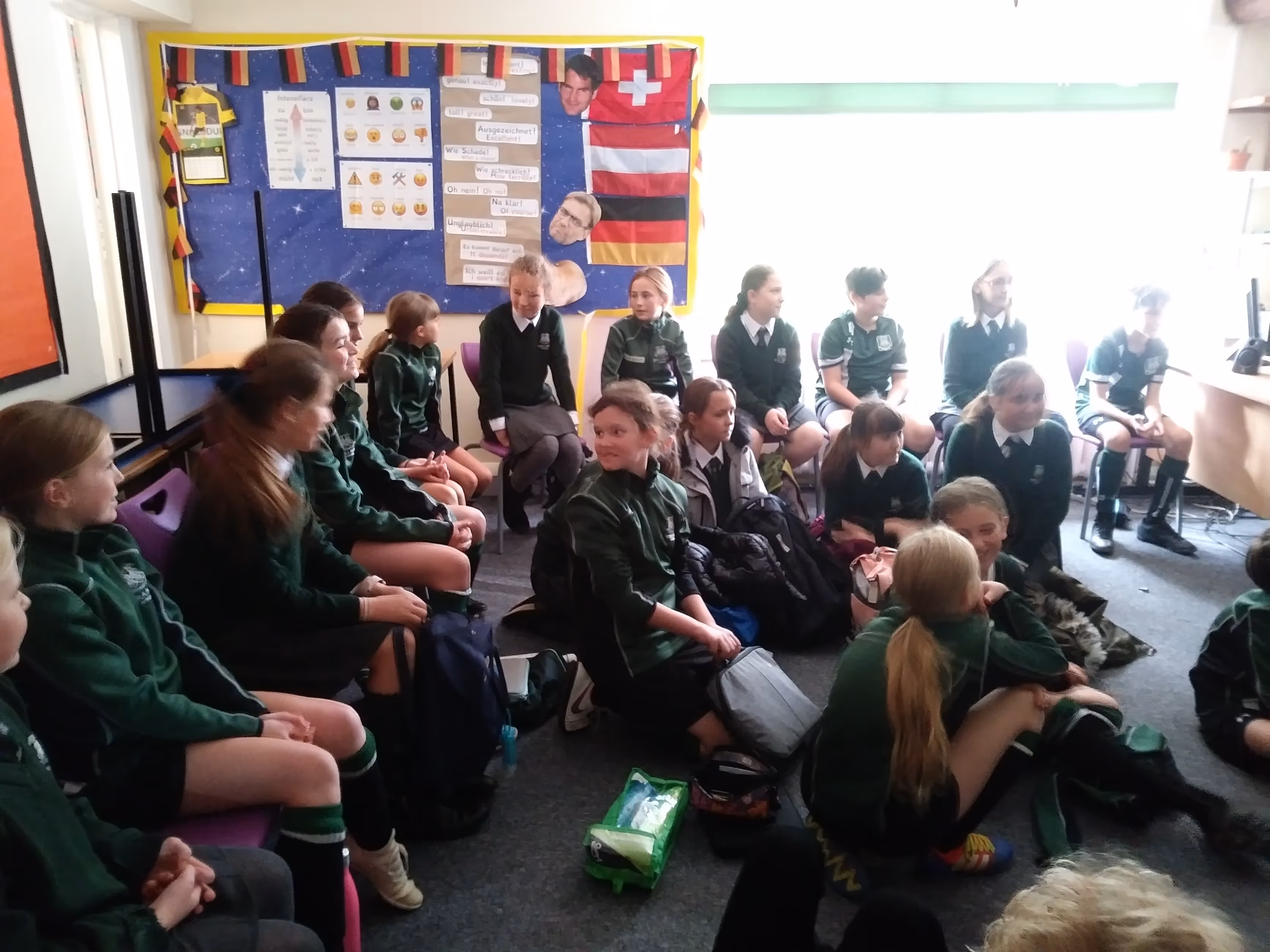 Die deutschen Schüler:innen sitzen mit den Austauschkindern in einem englischen Klassenzimmer.