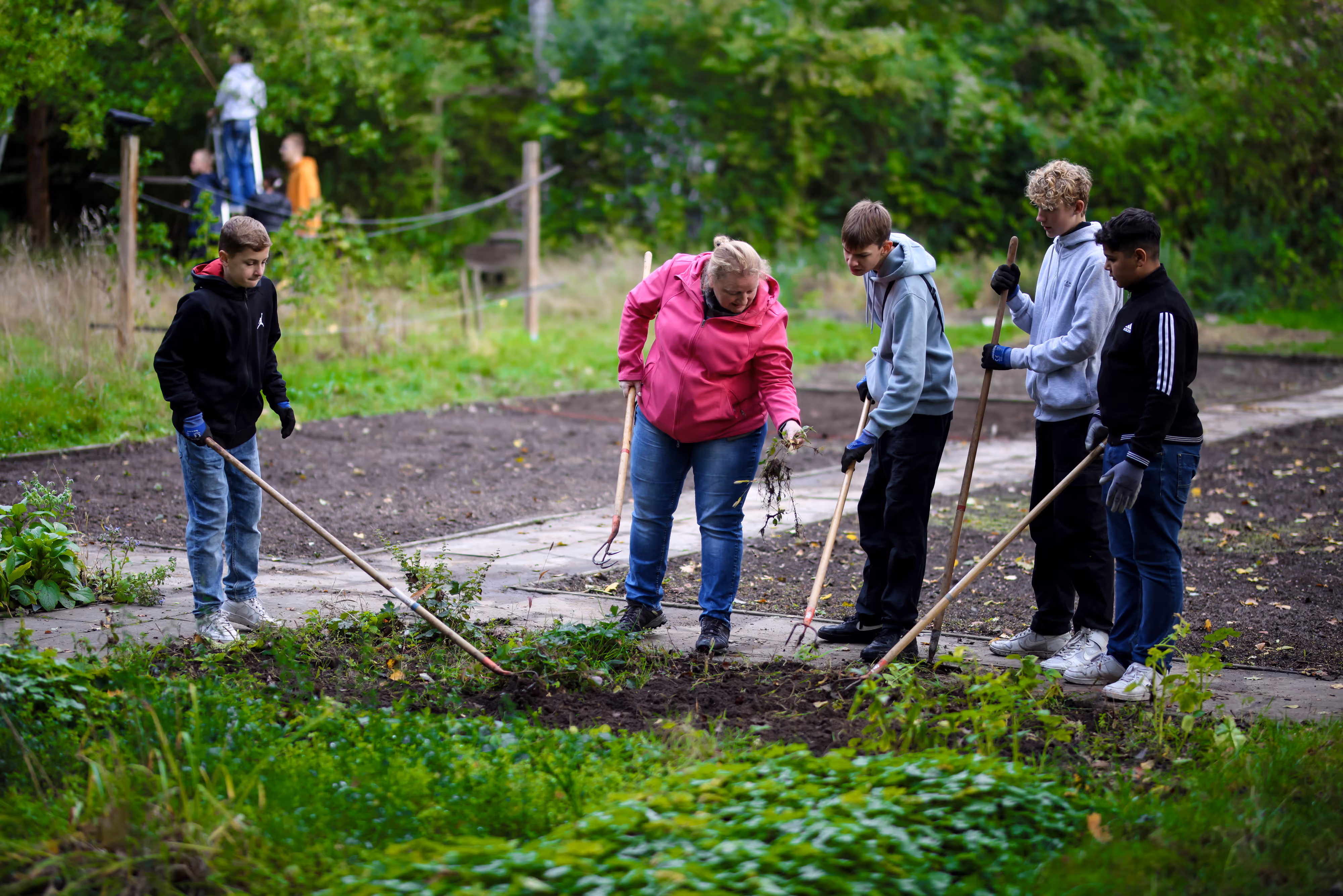 Schüler und Lehrerin im Schulgarten bei der Gartenarbeit 