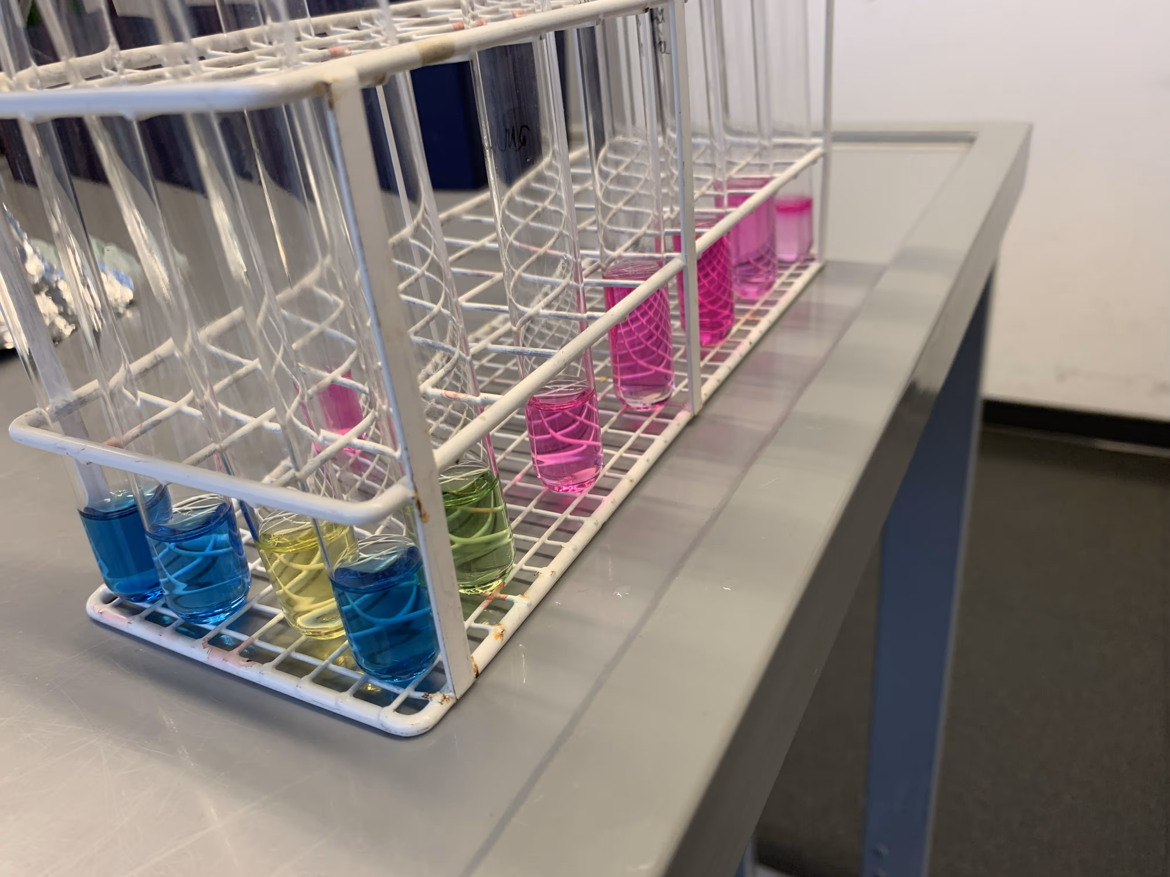 Verschiedene Reagenzgläser in einem Ständer mit farbenfrohen Füllungen