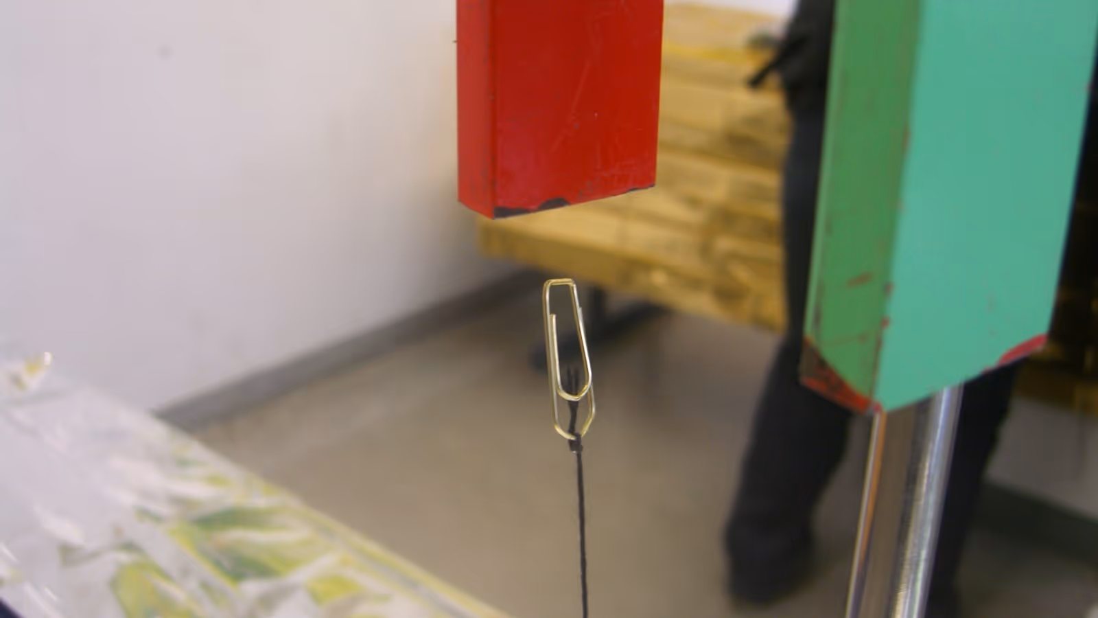 Eine Büroklammer wird kopfüber von einem Hufeisenmagneten angezogen