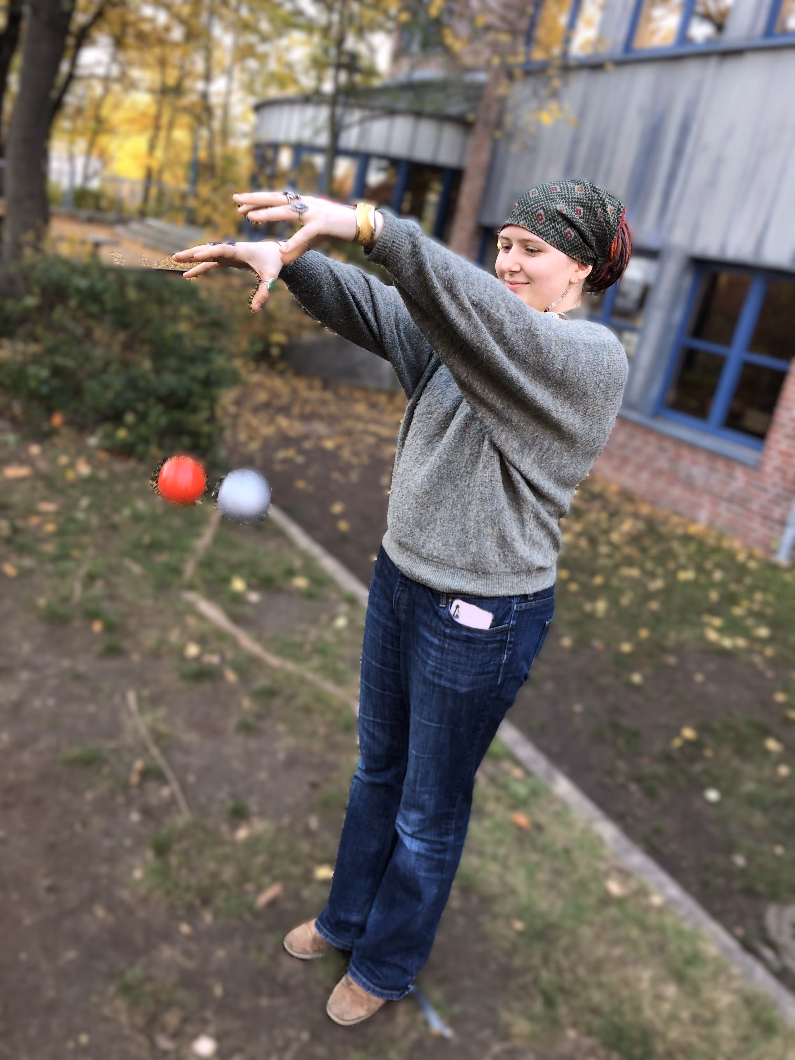 Eine Schülerin steht im Freien und lässt gleichzeitig zwei Bälle fallen