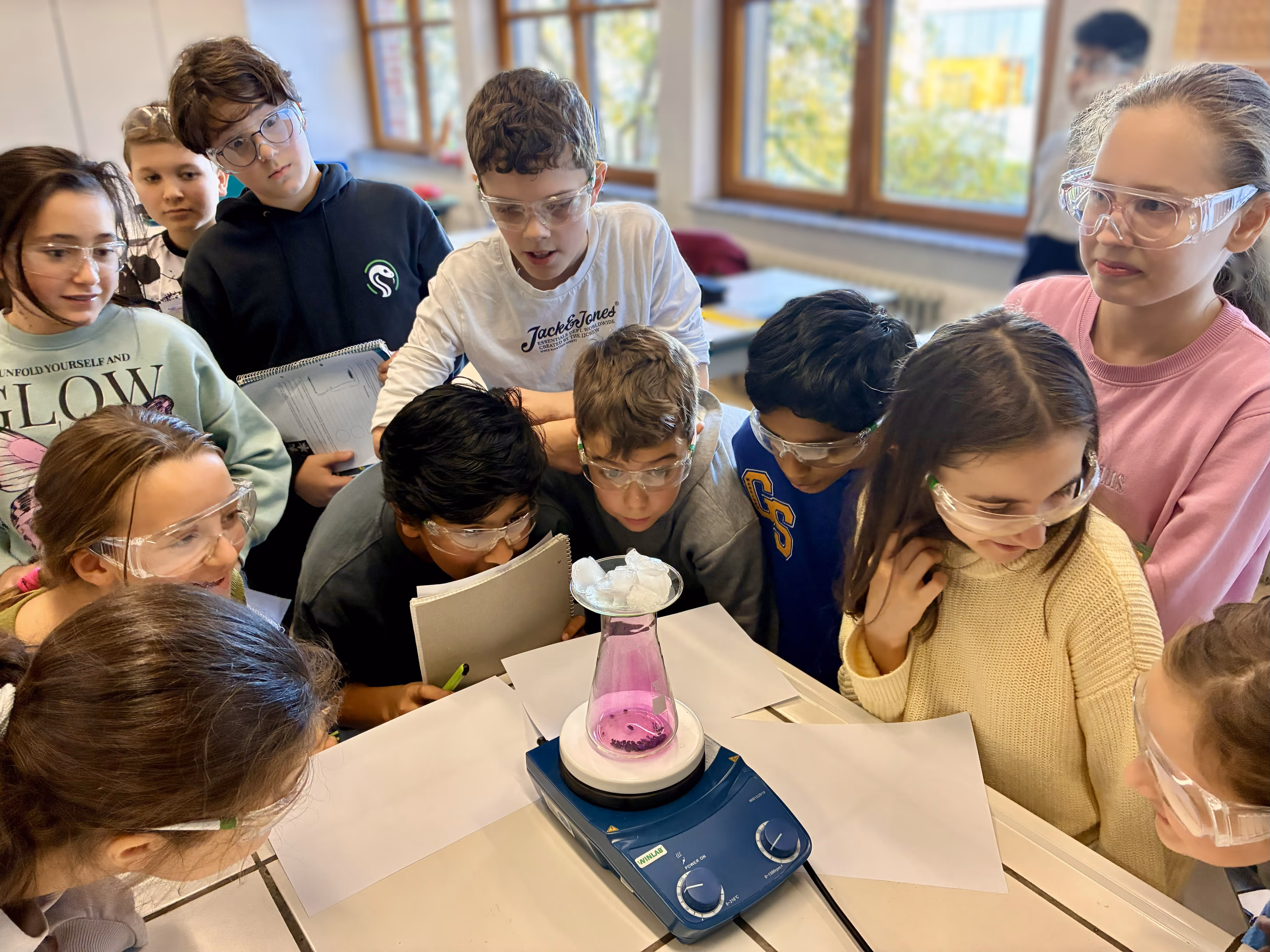 Eine Gruppe von Schülern guckt sich begeistert ein Experiment an.