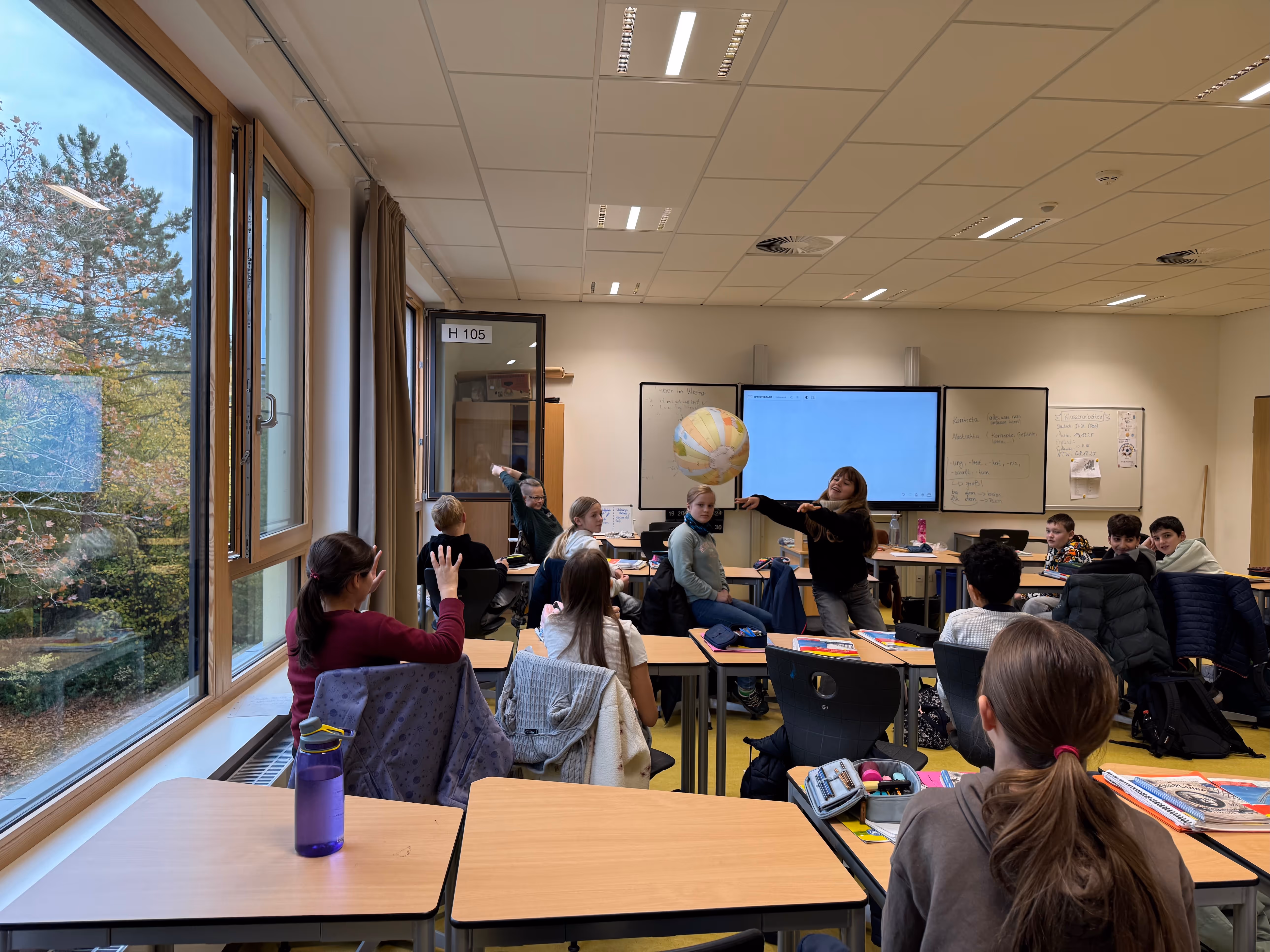 Eine Szene im Spanischunterricht. Die Kinder werfen sich gegenseitig eine Weltkugel zu und üben so die Konjugation verschiedener Verben. 