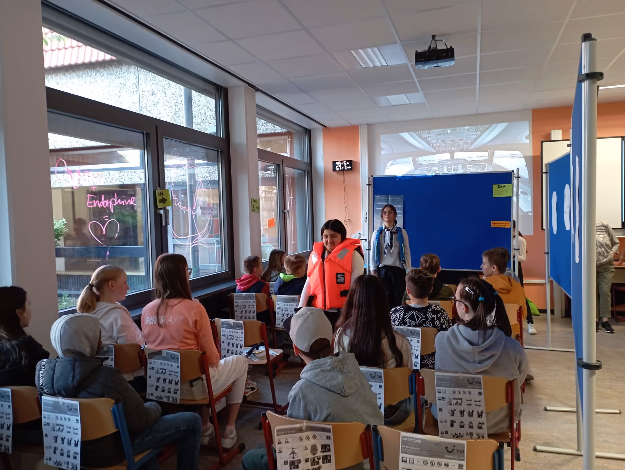 Eine Szene aus dem Sprachendorf, die Schüler:innen spielen einen Flug im Flugzeug nach.