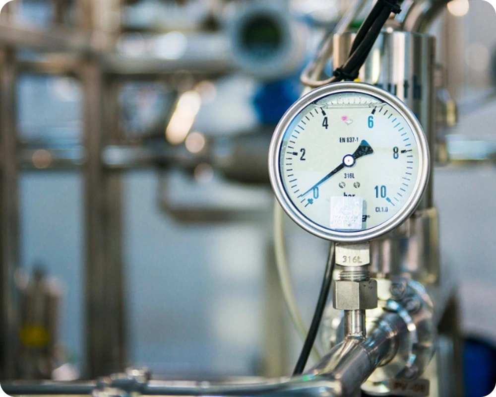 Manomètre métallique connecté à un tuyau en acier inoxydable dans une installation industrielle.