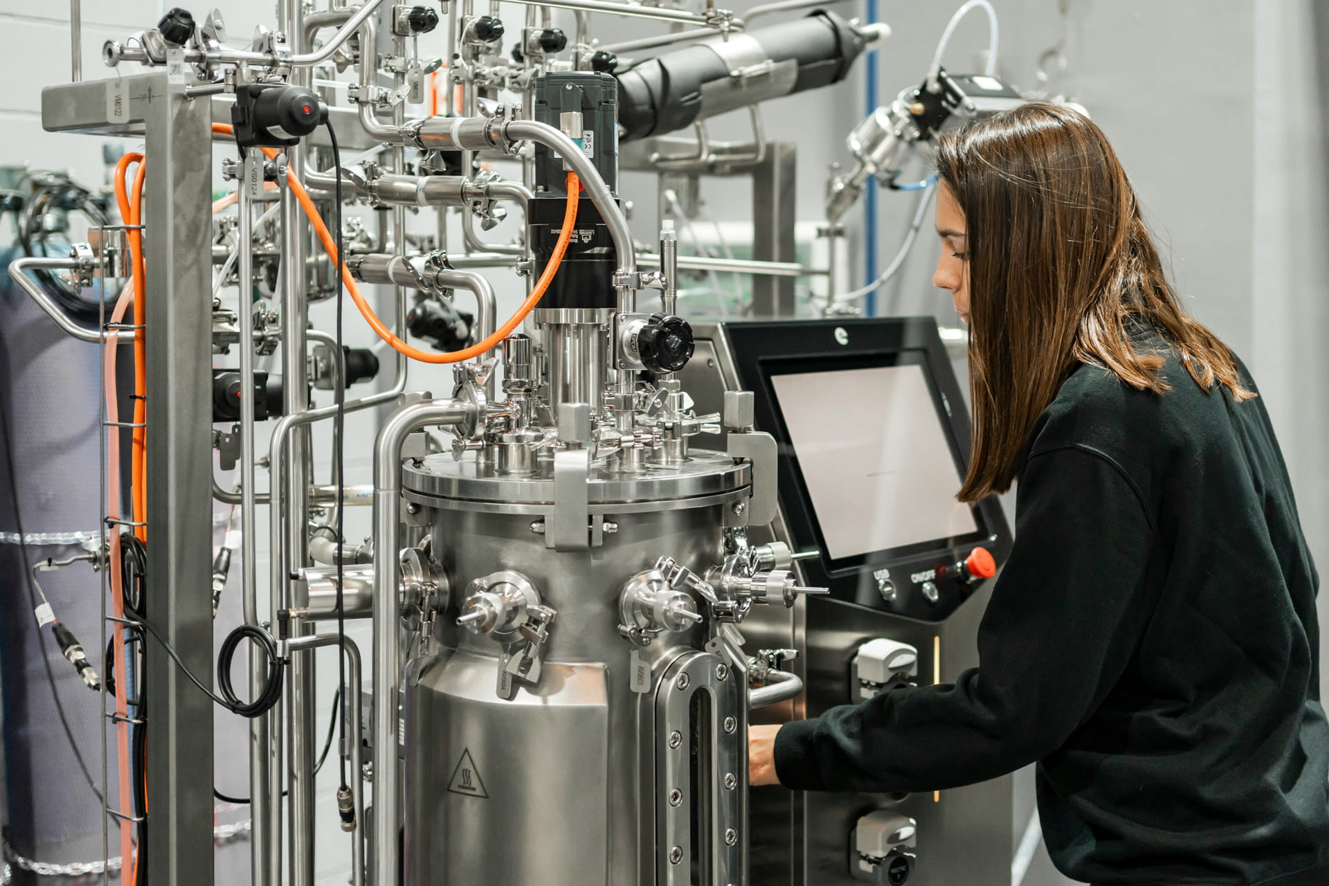 Technicienne utilisant une machine industrielle avec écran tactile dans un laboratoire.