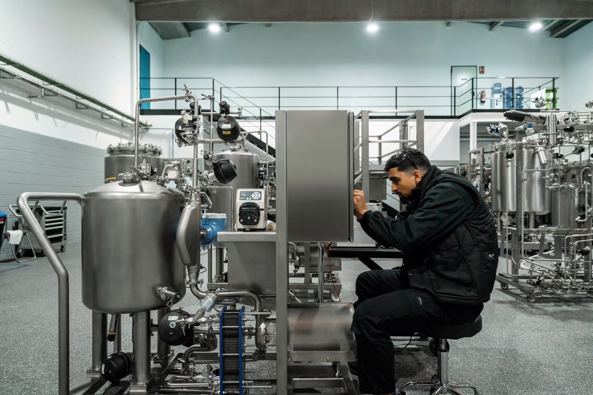 Technicien en veste noire assis, travaillant sur une machine industrielle.