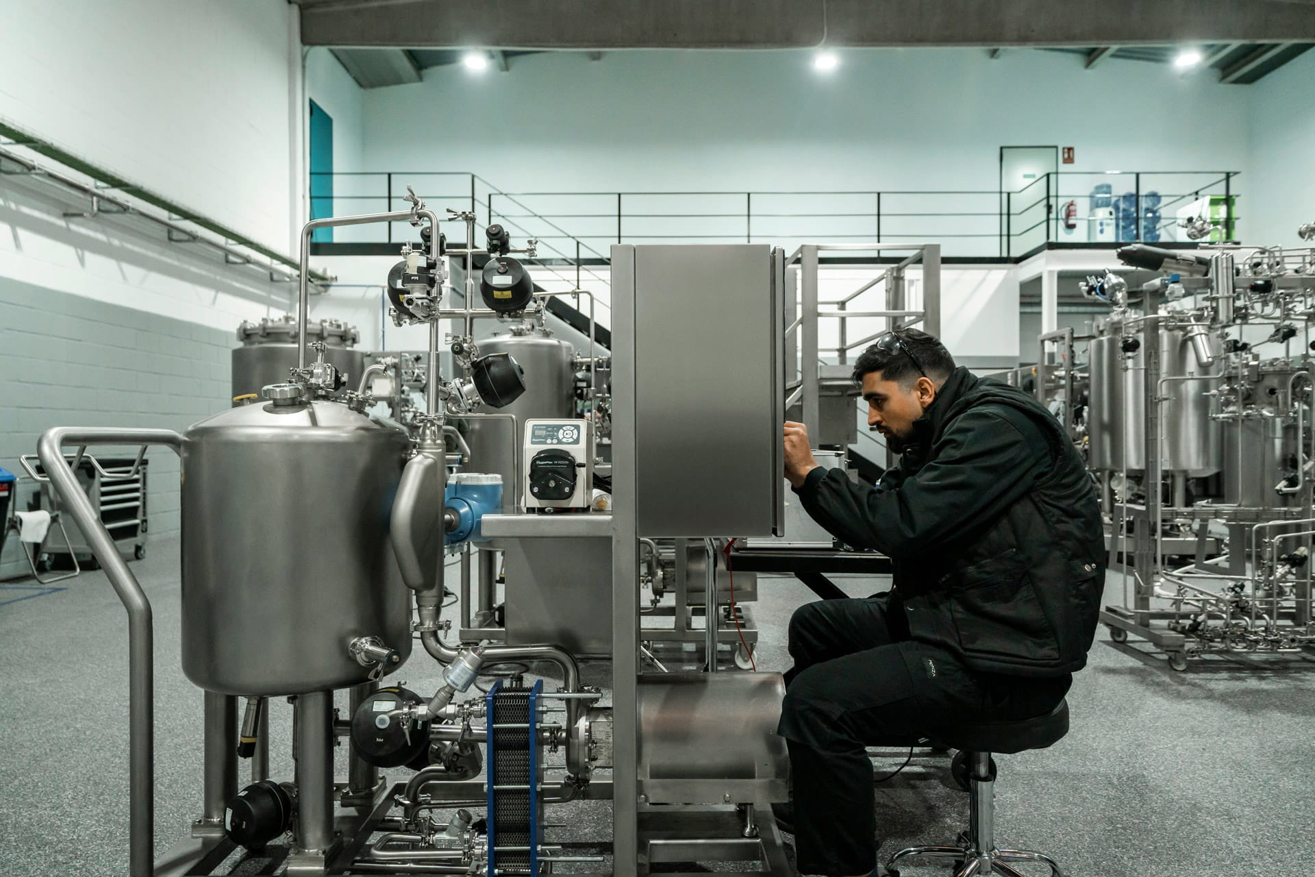 Technicien en veste noire assis, travaillant sur une machine industrielle.