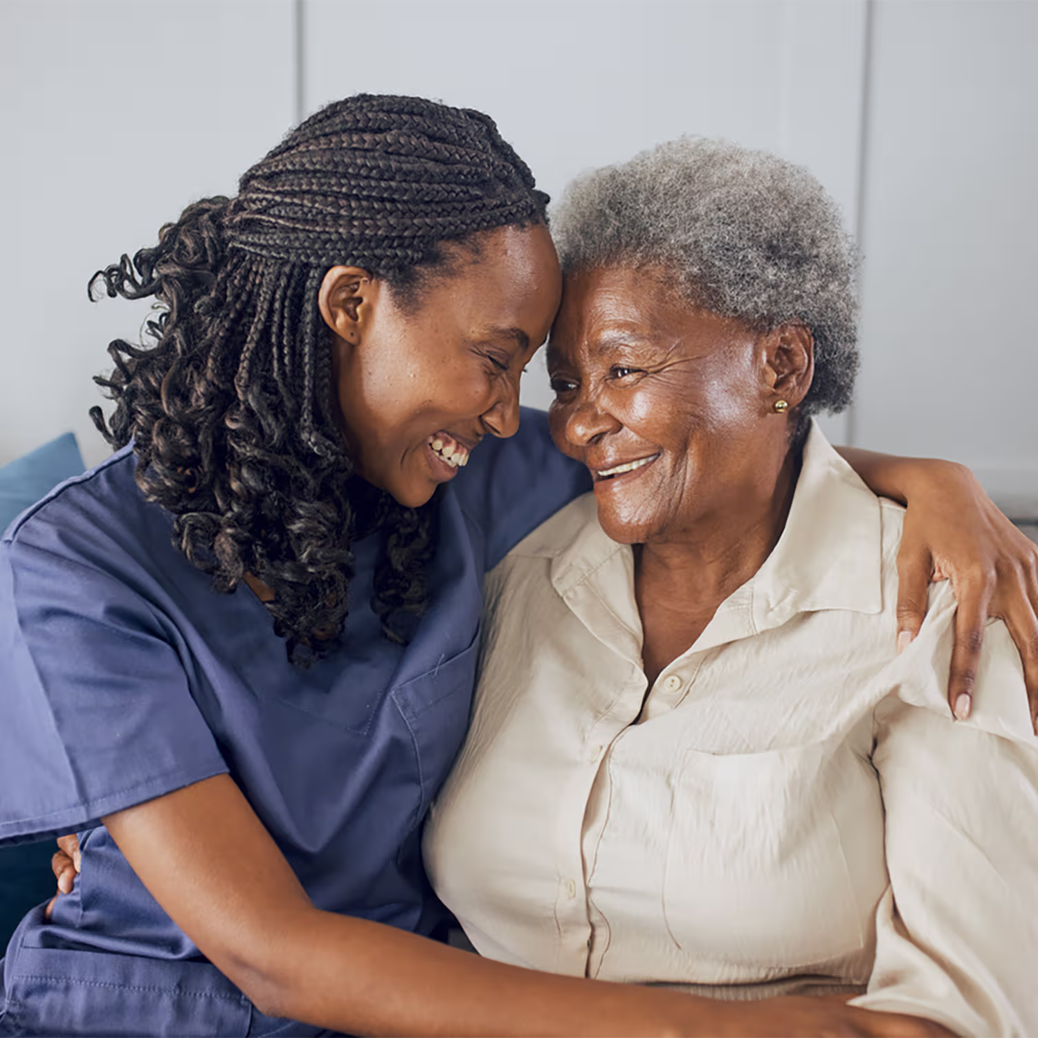 Smiling young nurse embracing an elderly woman in a caring and affectionate manner.