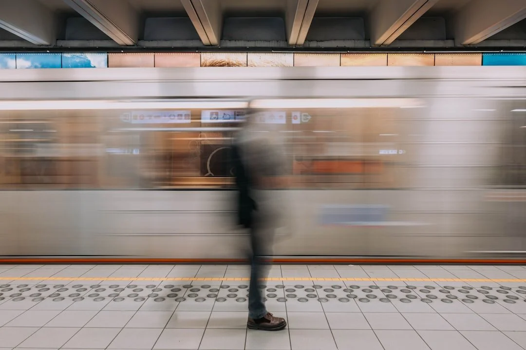 Blurred person standing on a subway platform as a train speeds past.
