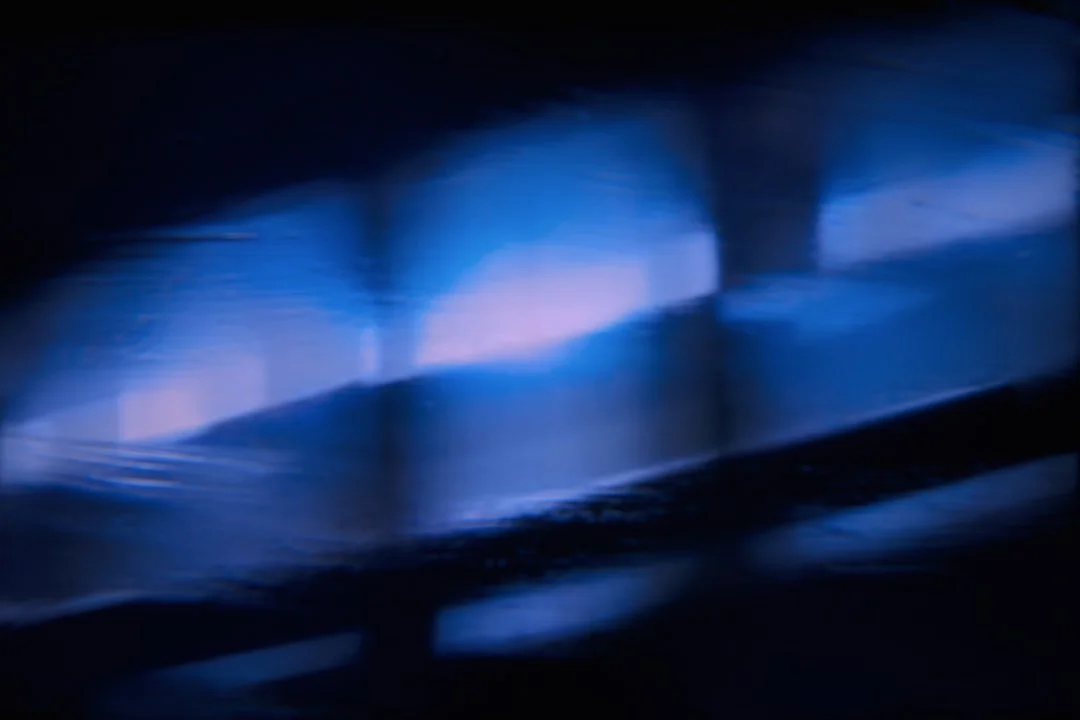 Abstract image with blue and black hues featuring blurred light and shadow patterns.