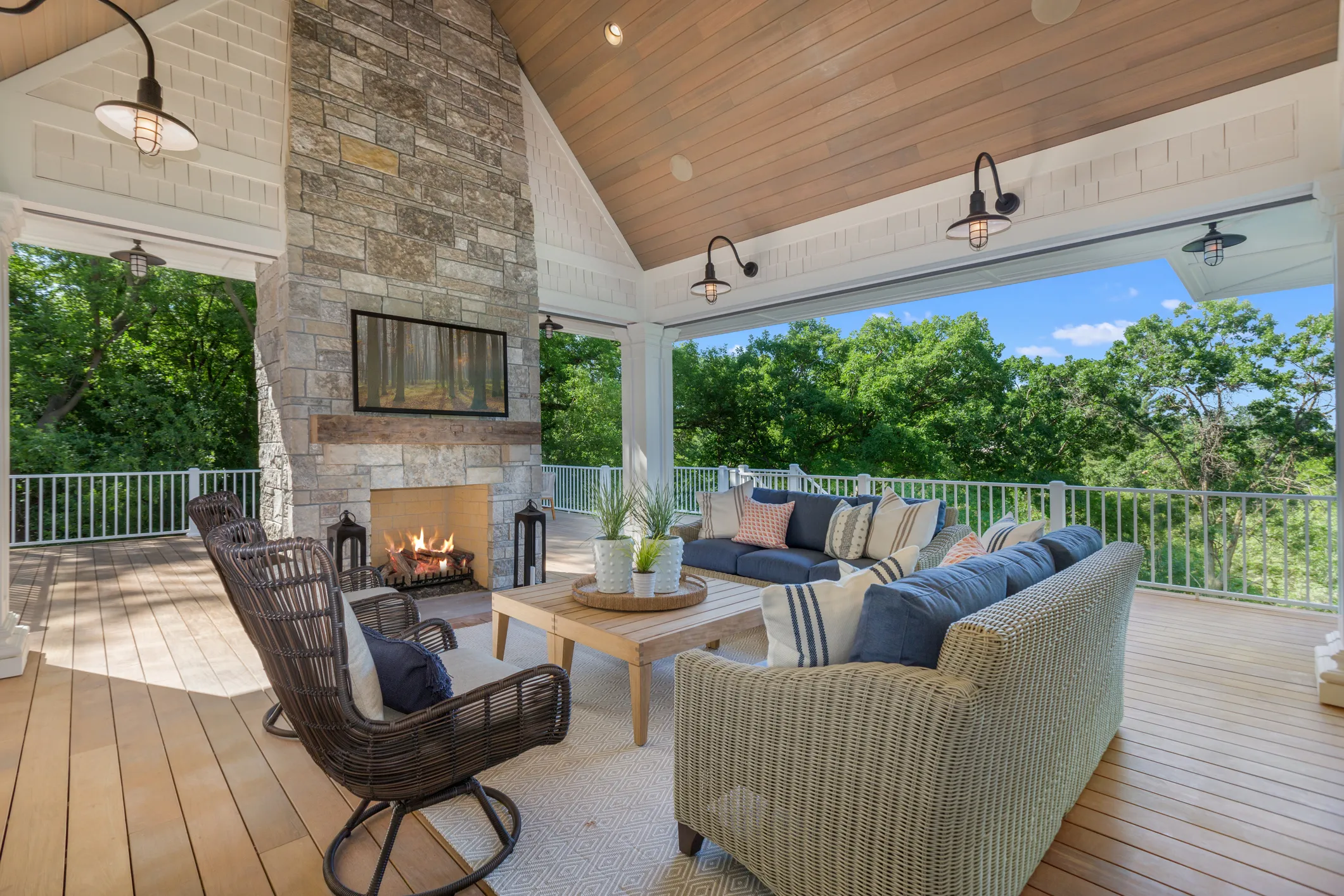 Covered outdoor living area with fireplace, TV, and patio seating