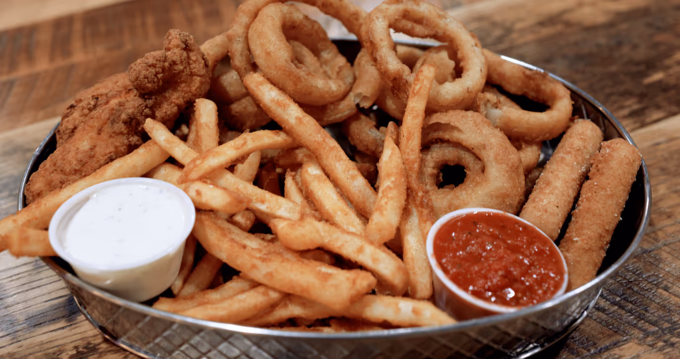 Appetizer sampler tray with french fries, onion rings, mozzarella sticks and chicken tenders.